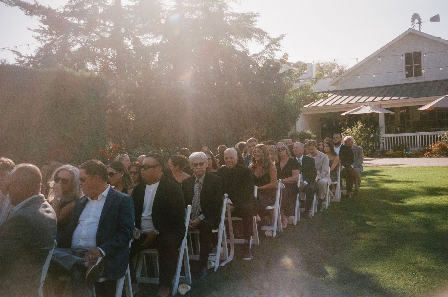 Wedding ceremony setup with white chairs arranged outdoors at sunset.