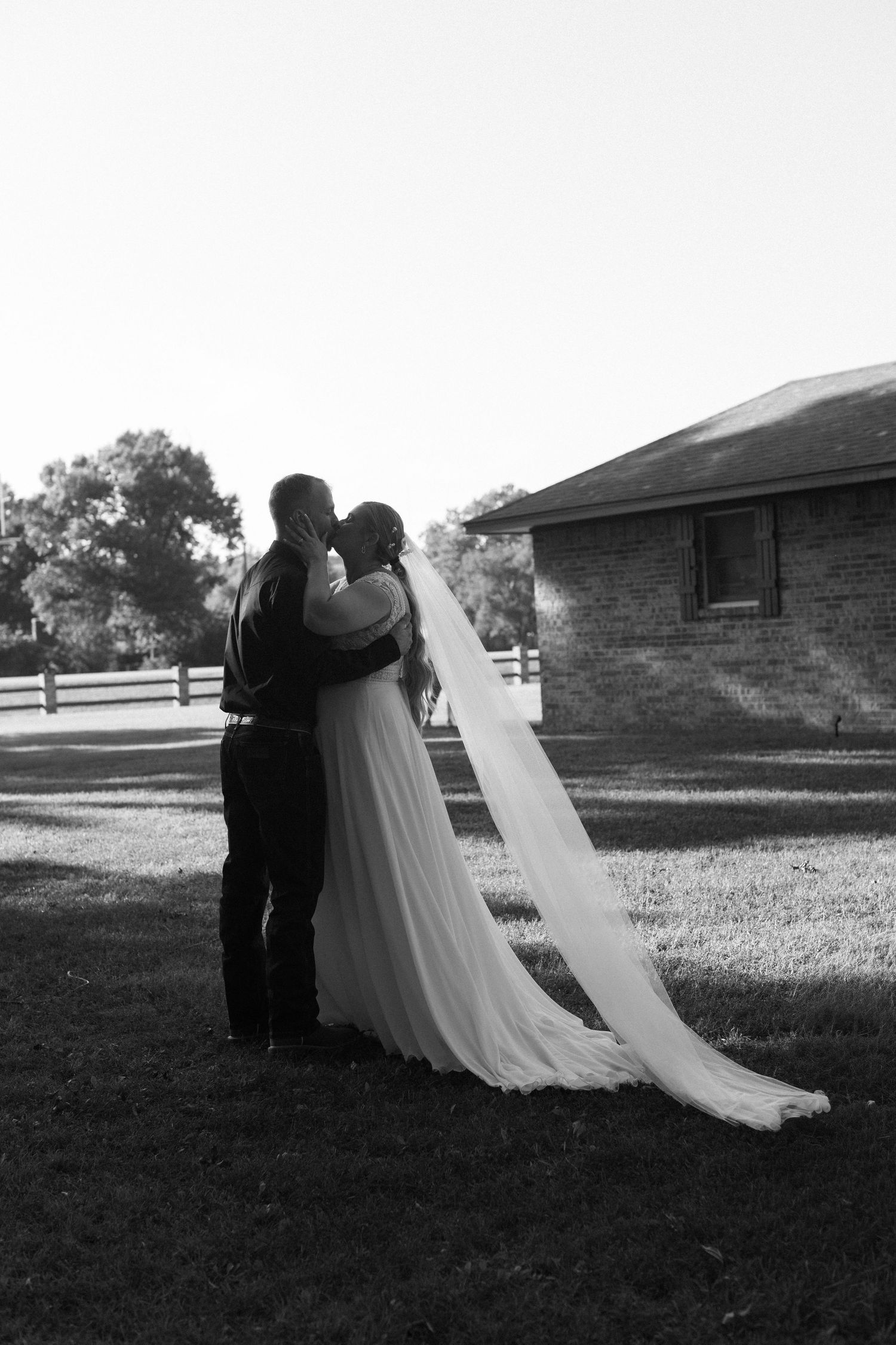 Black and white silhouette of wedding couple embracing outdoors.