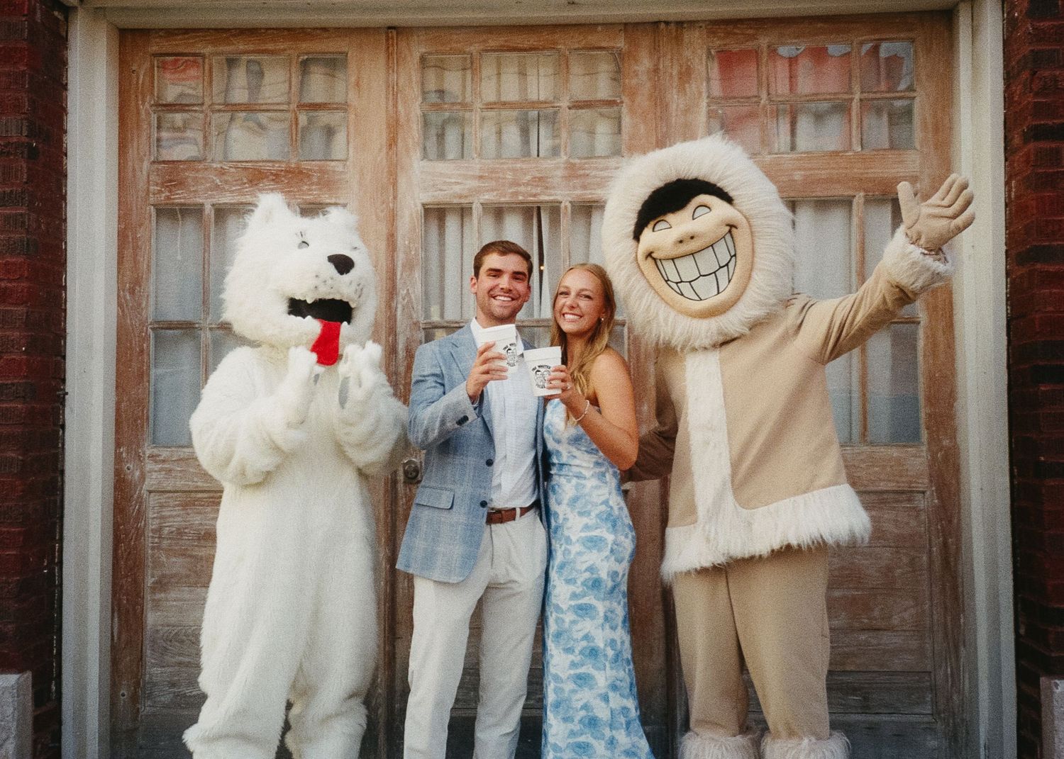 A group poses for a fun photo with people in costumes against a brick building.