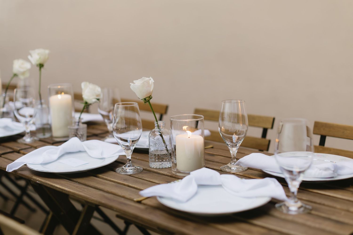 Elegant table settings in a restaurant with white plates, wine glasses, and neutral toned decor create an inviting atmosphere.