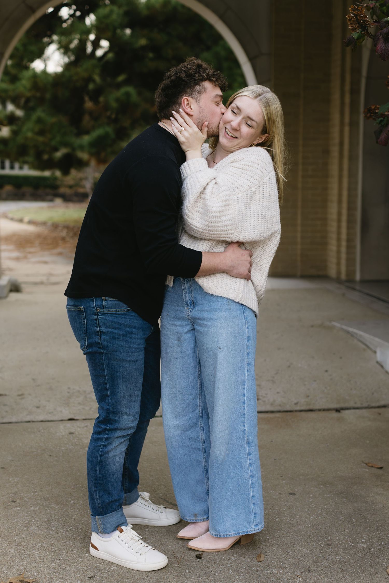 A couple shares intimate moments under a covered walkway with brick columns.