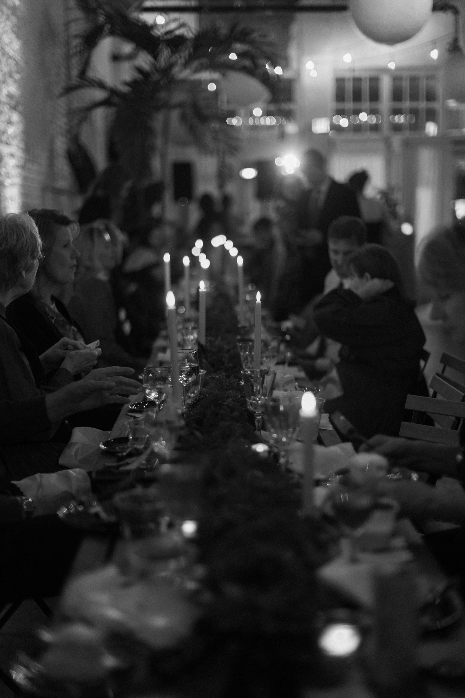 Dimly lit wedding reception dinner table with glowing candles and ambient lighting creating romantic atmosphere.