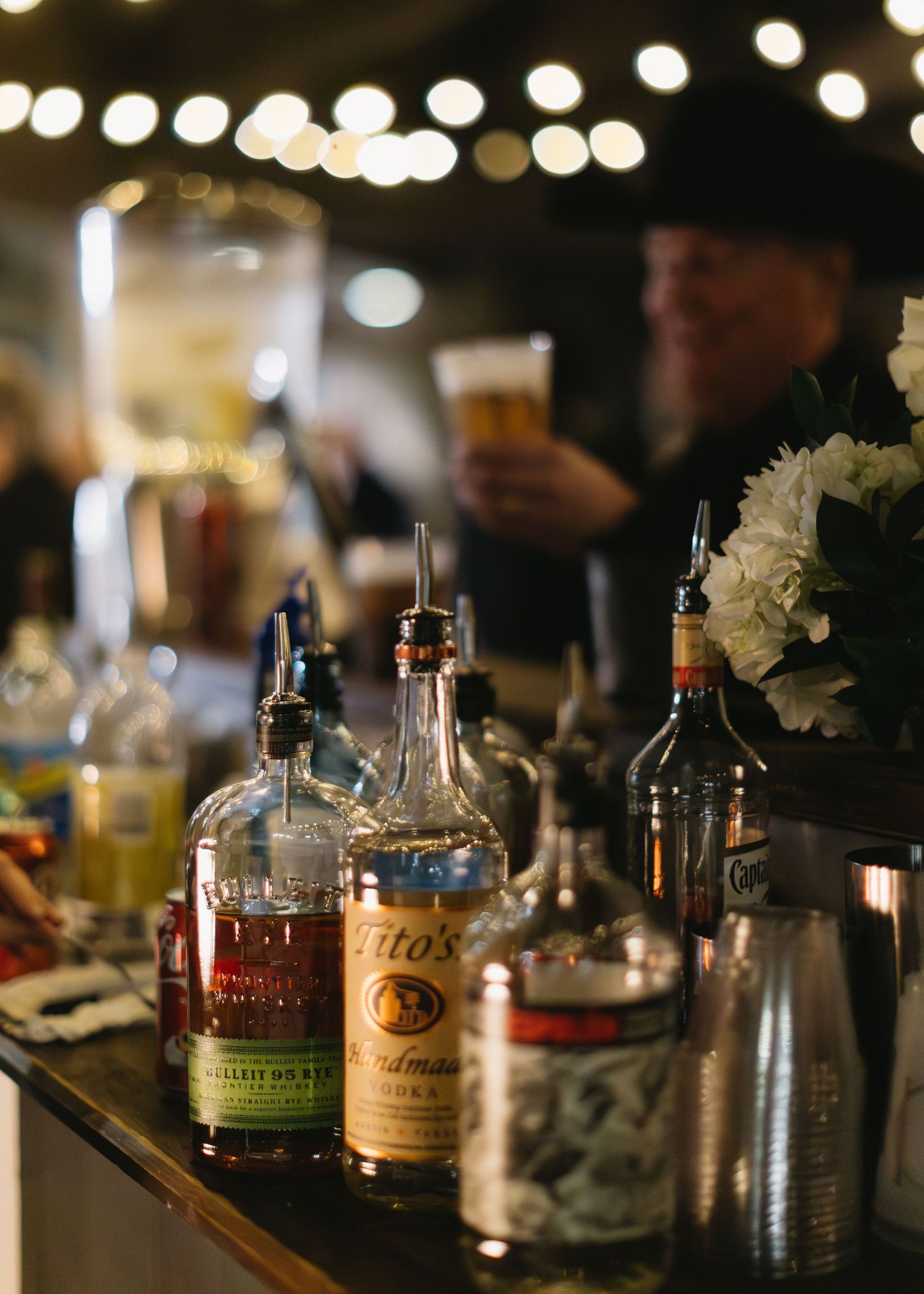 Various liquor bottles and cocktail ingredients arranged on an elegant bar at a wedding reception.