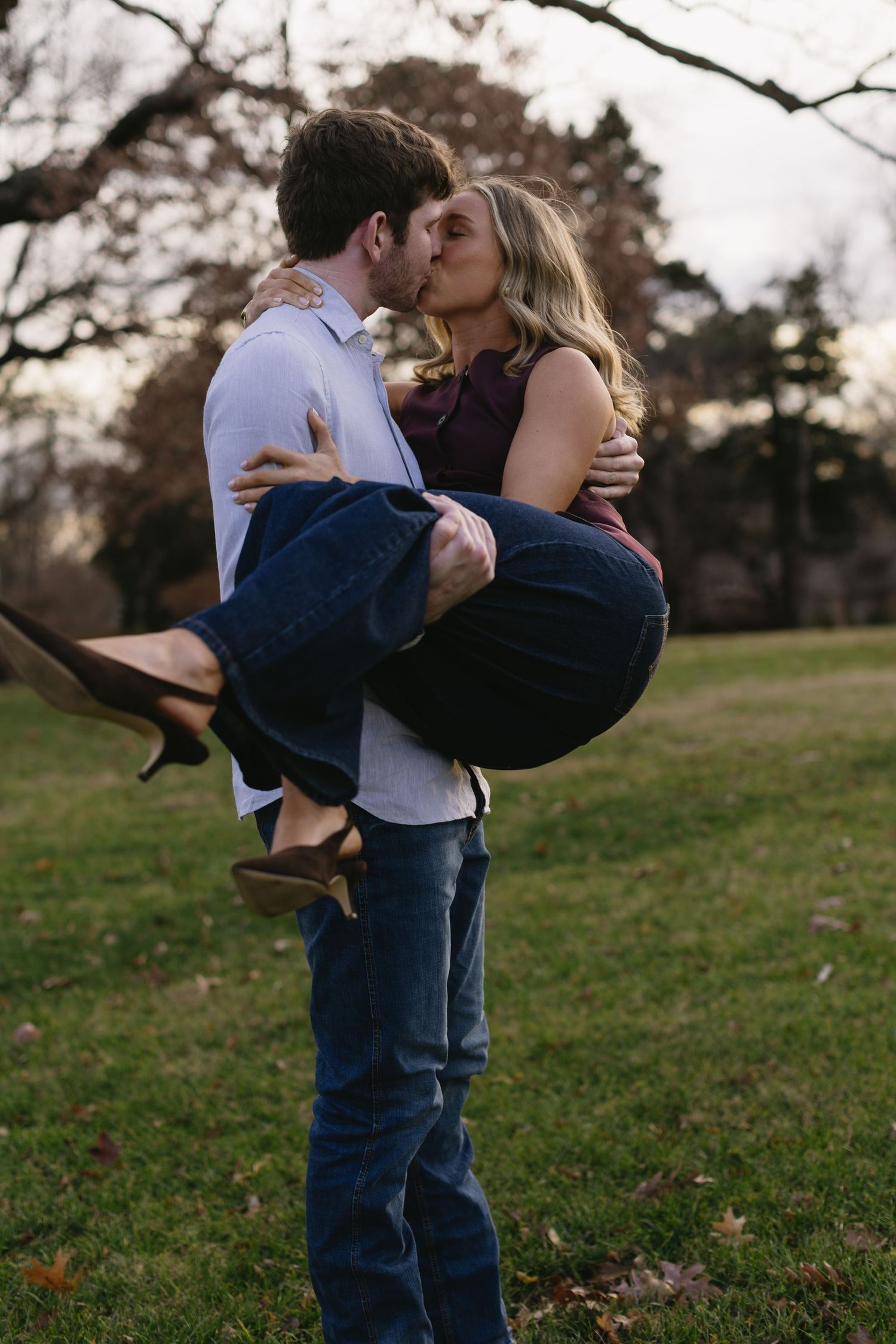 Romantic moment captured as couple embraces in a lifting pose on grass.
