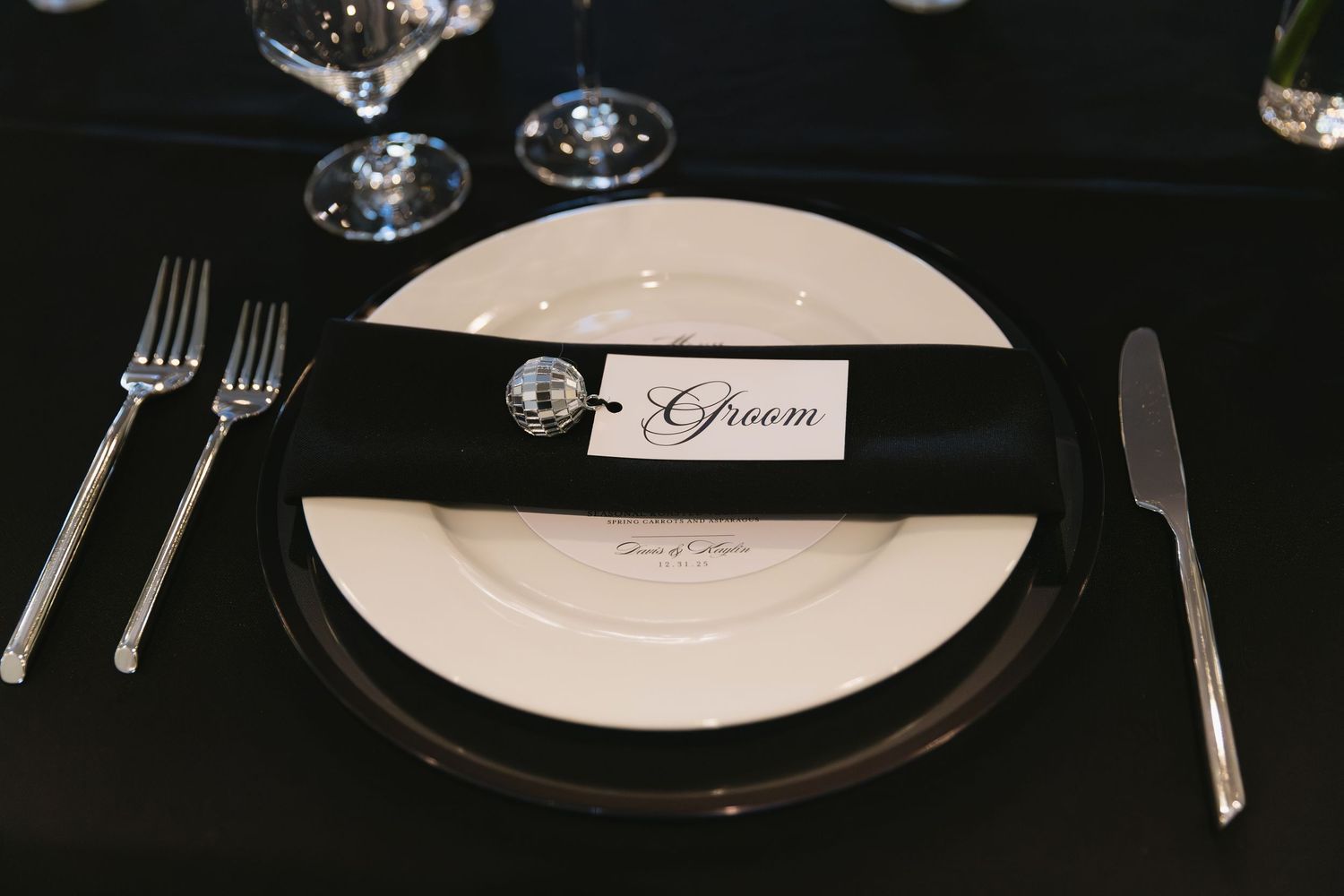 Elegant place settings with white plates and name cards at a formal wedding reception.