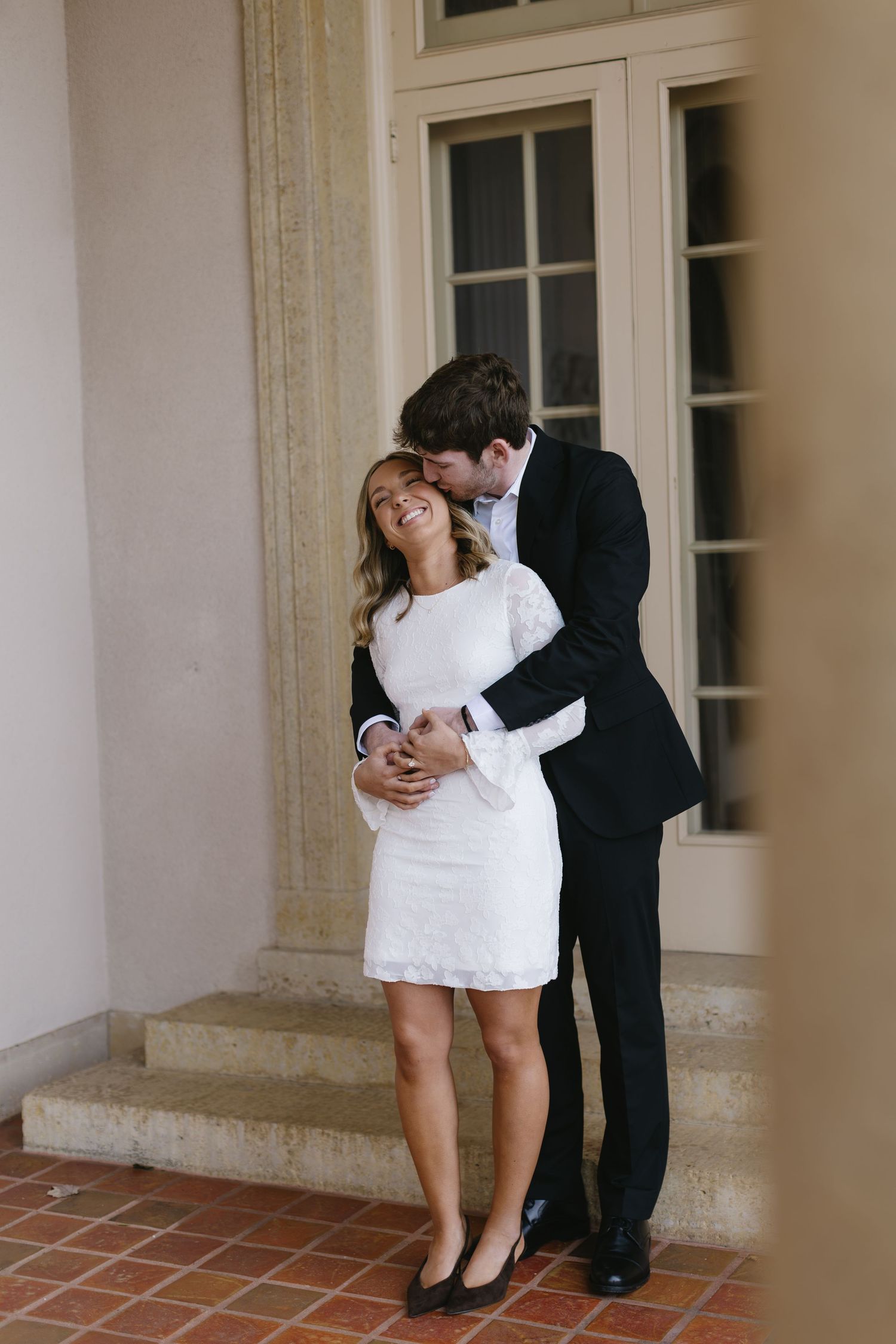 A romantic sequence of wedding photos showing a couple in formal attire embracing in a hallway with white columns.