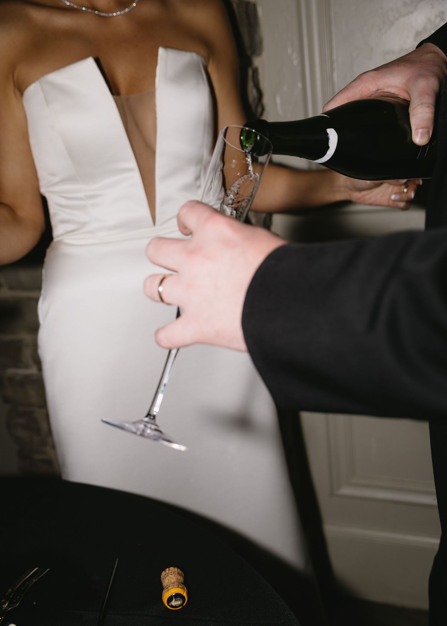 Close-up of champagne glasses being handed between guests at a wedding celebration.