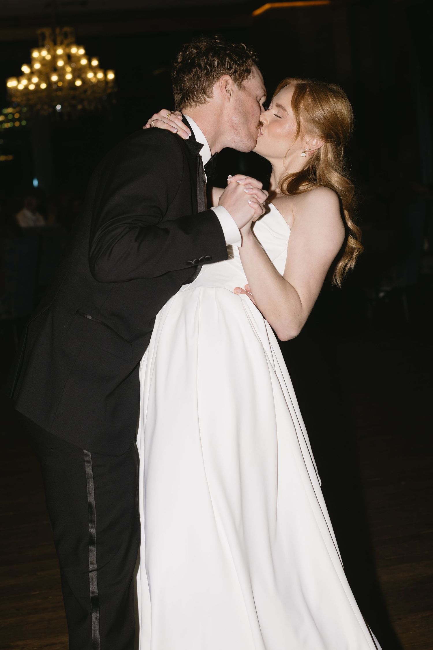 A romantic evening moment captured between newlyweds with twinkling lights in the background.