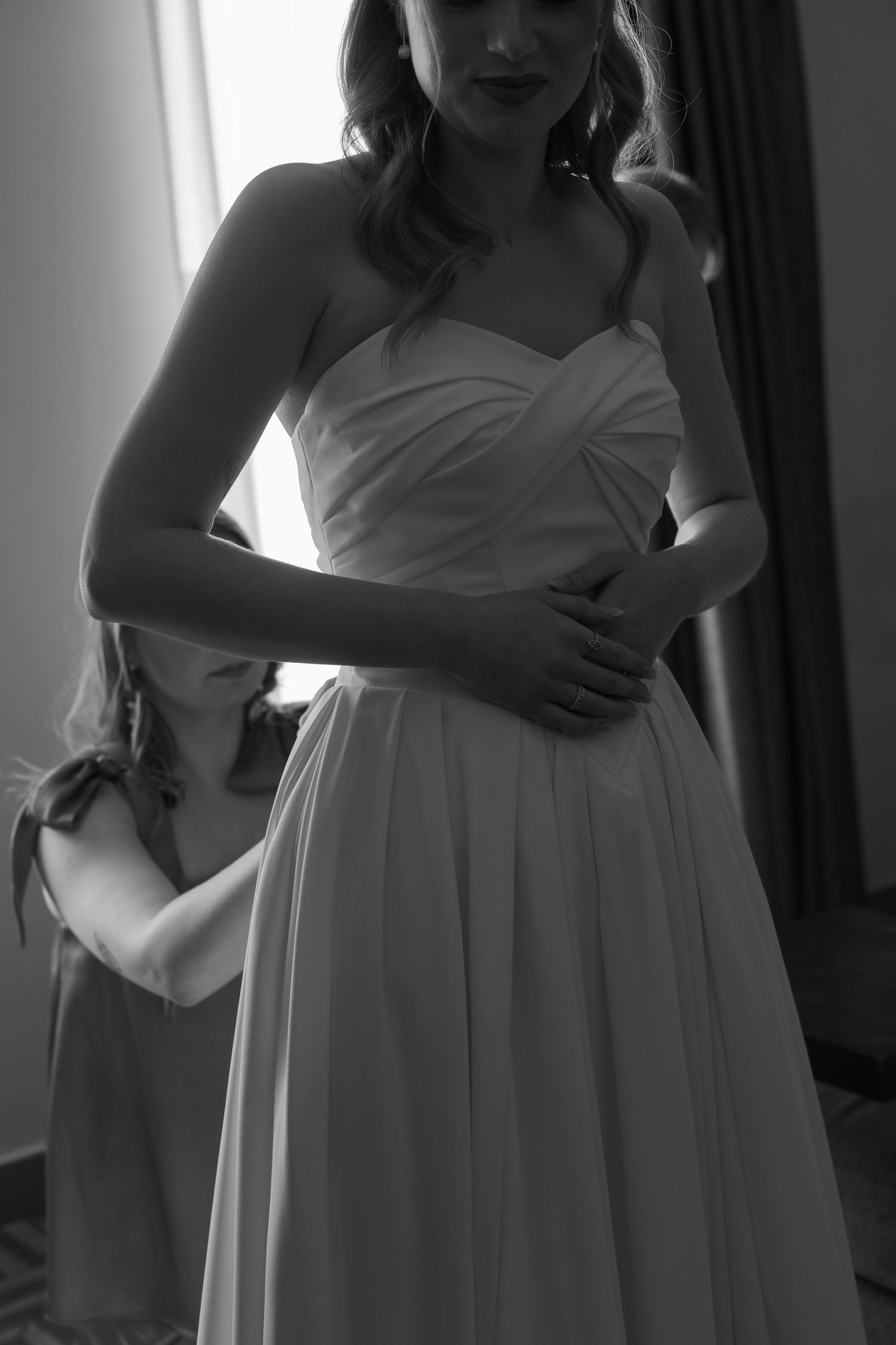 Black and white image of someone in an elegant white dress preparing for a special occasion.