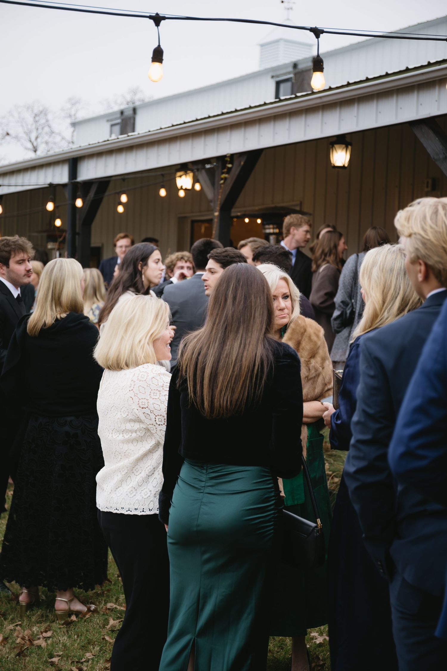 Wedding guests gathered outside venue wearing formal attire on an autumn day.