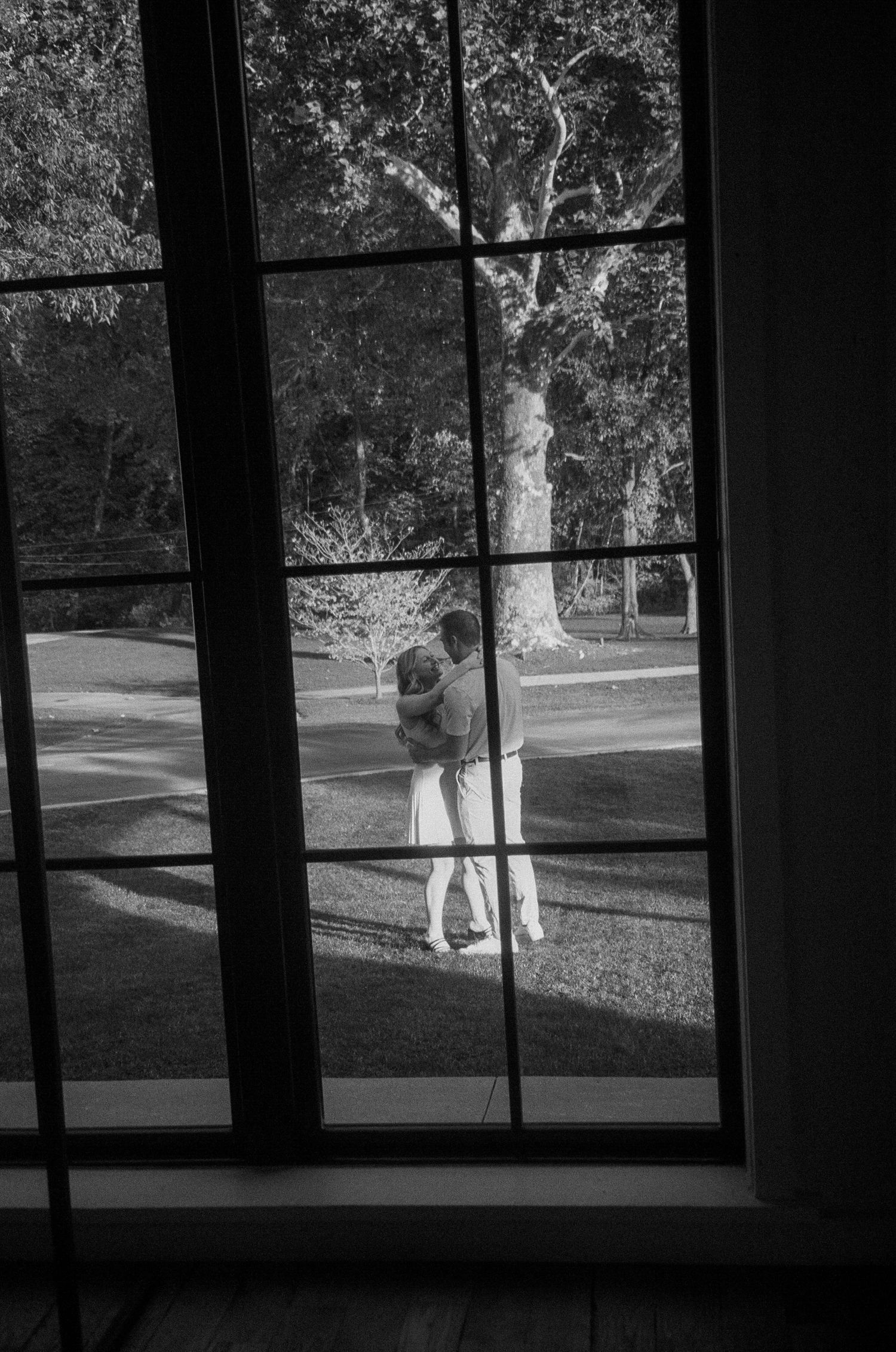 Silhouetted figures stand behind window panes in a black and white photograph.