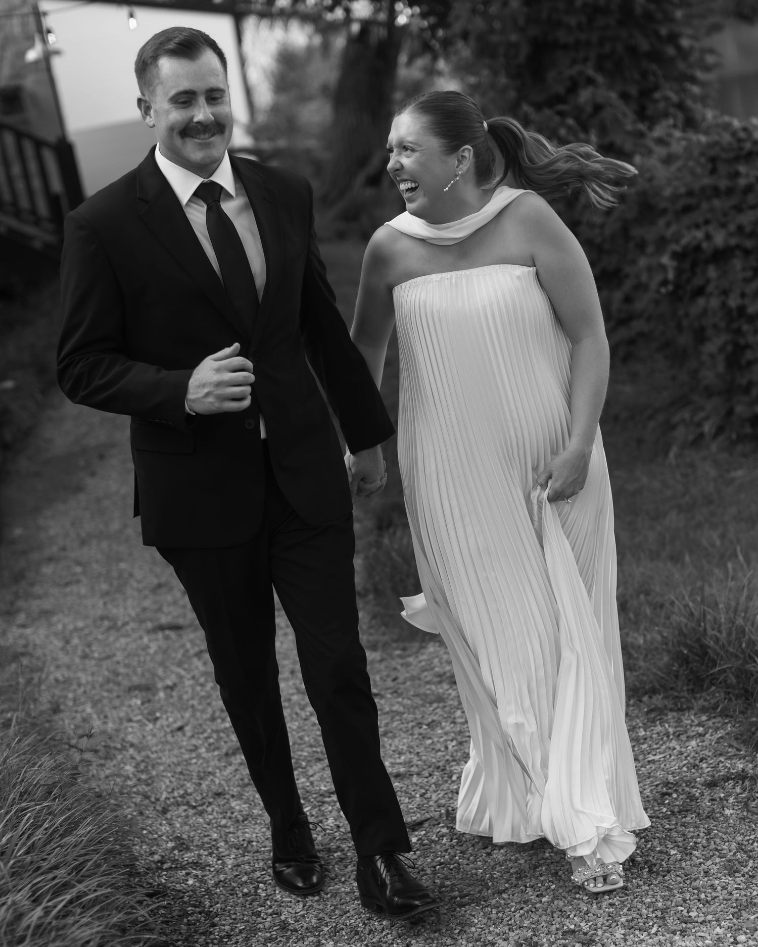 A black and white portrait of a couple walking and laughing together.