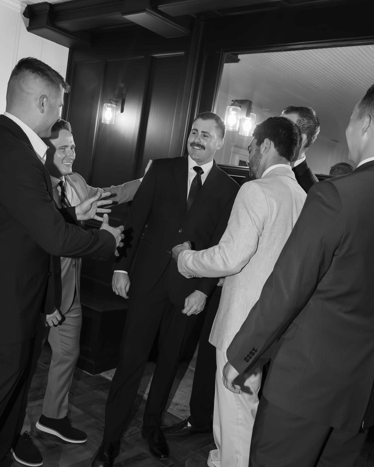 Group of people in formal attire conversing in a dimly lit hallway.