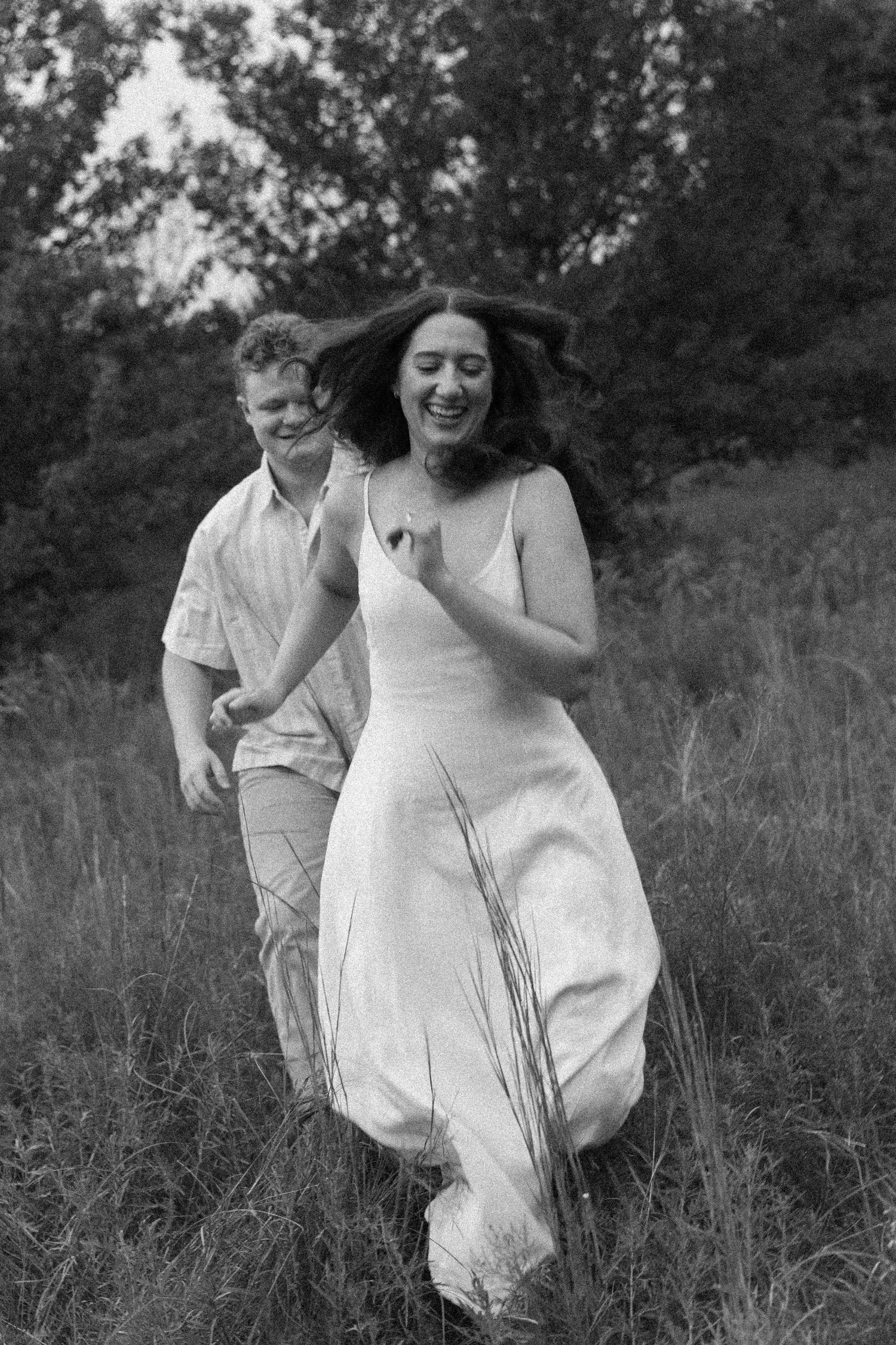 Black and white photos of a joyful couple running through a grassy field.