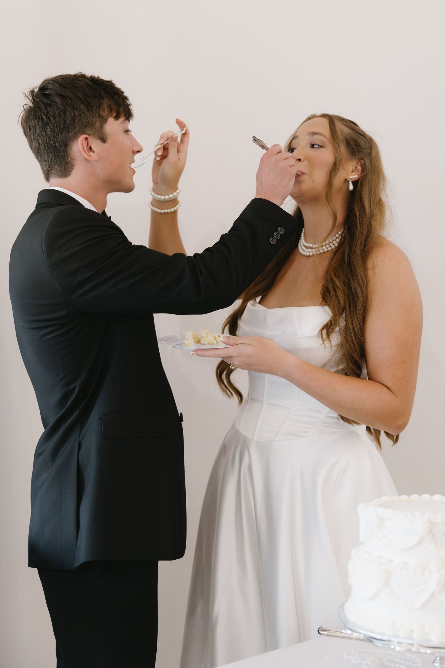 Playful moment of couple feeding each other wedding cake at their reception.