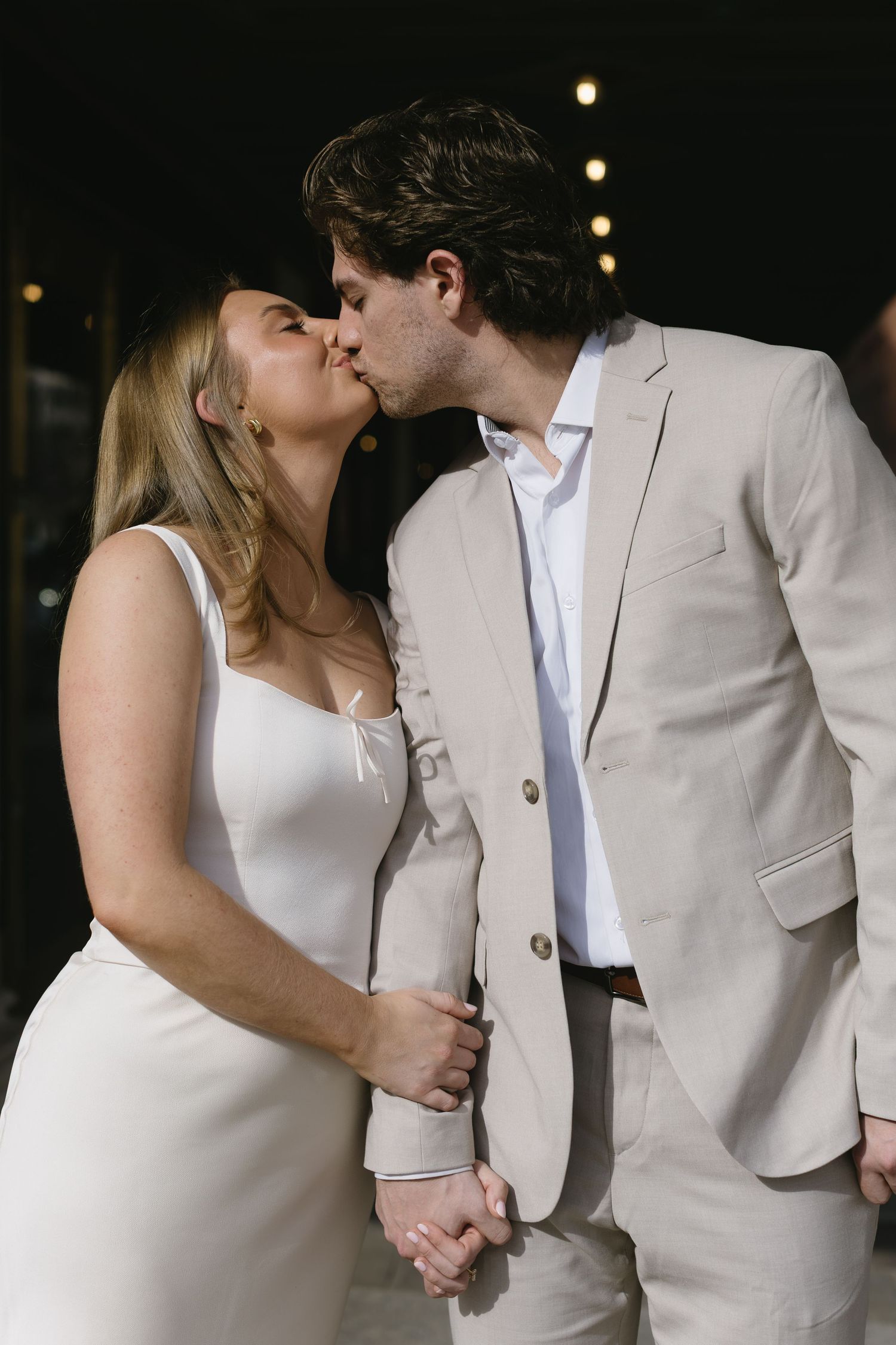 A couple shares romantic moments in evening lighting wearing coordinated formal attire.