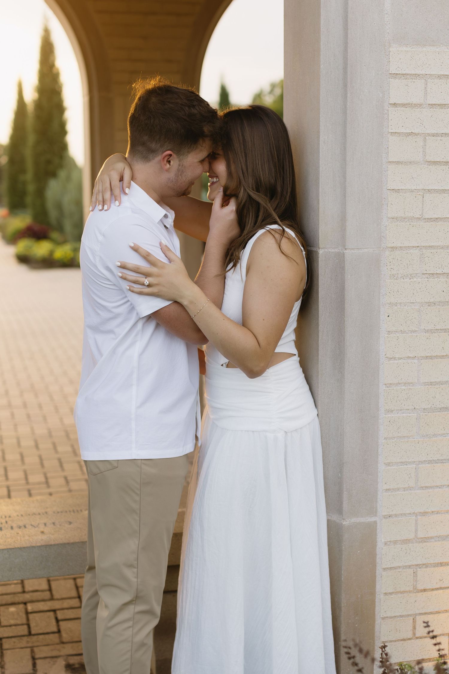 A couple shares an intimate moment under an elegant white archway.