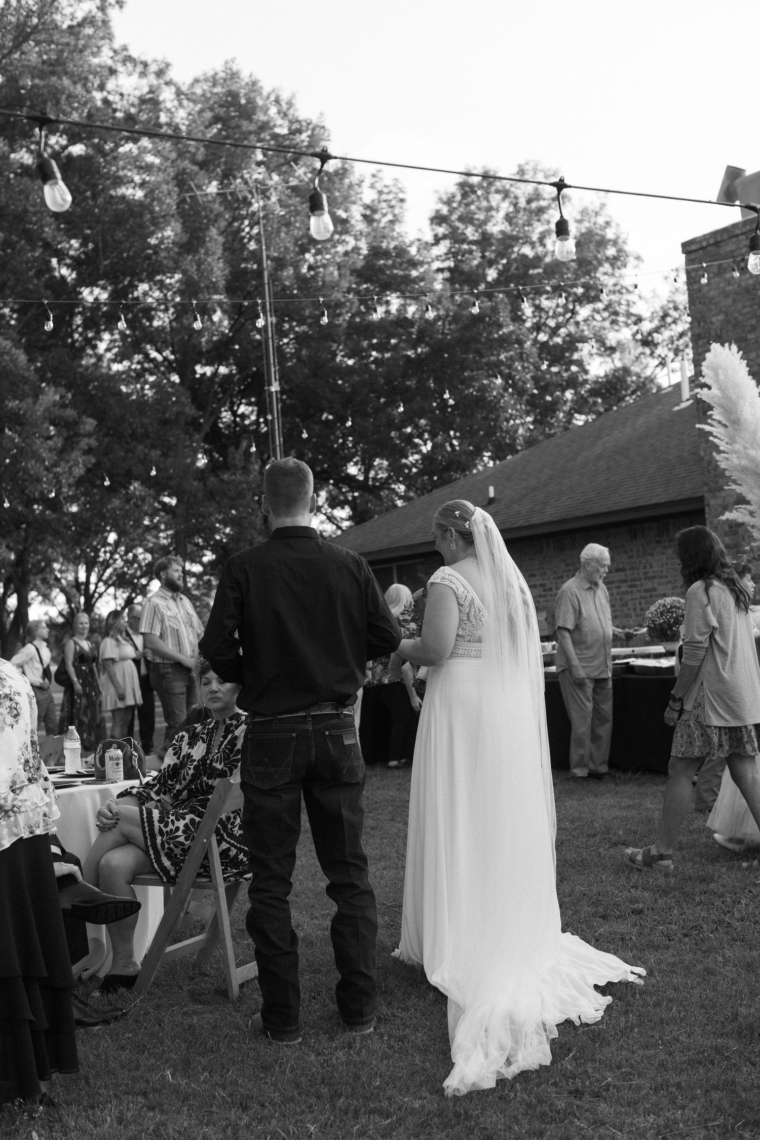 Black and white photo of wedding guests gathering outdoors during ceremony.