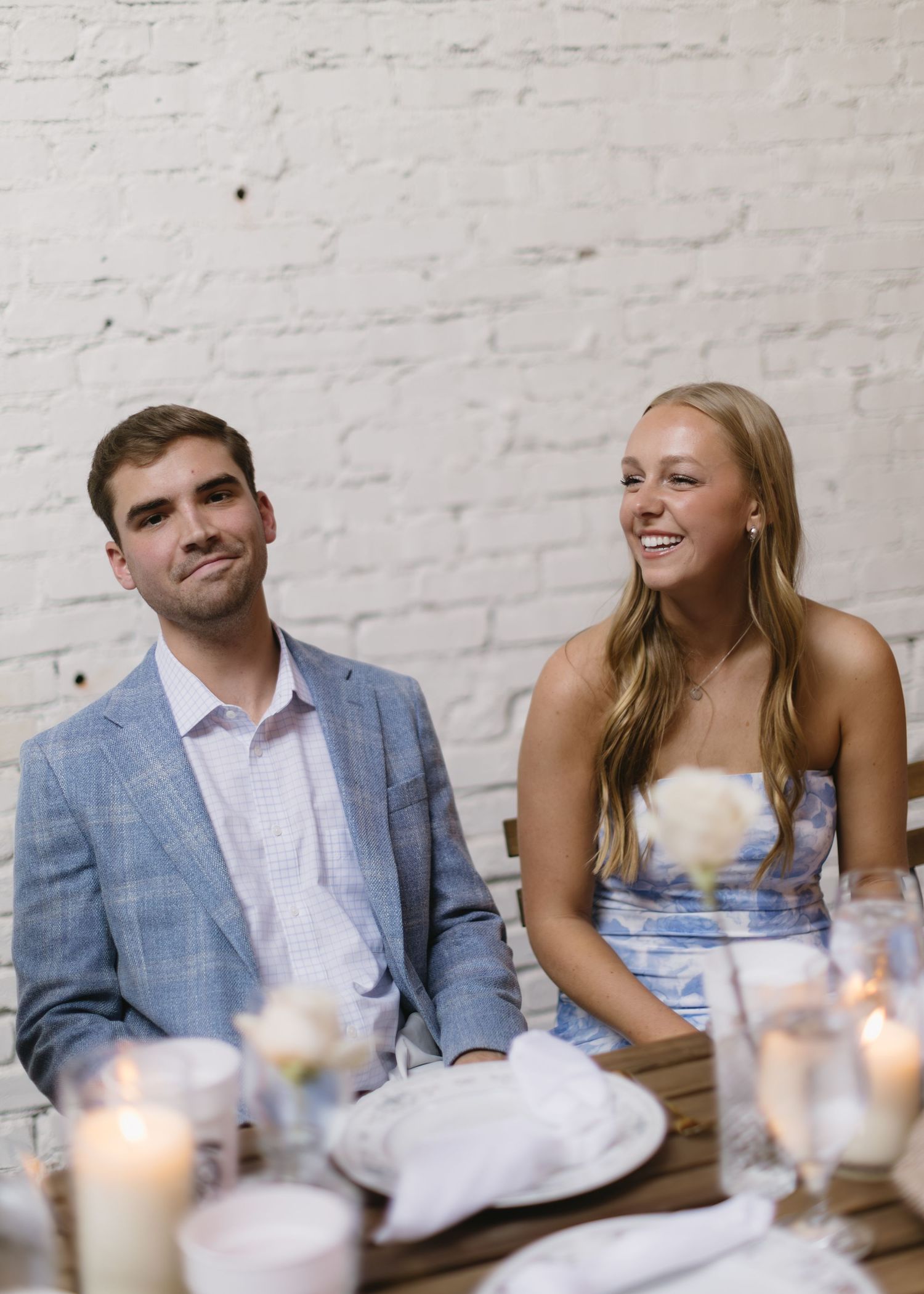 A couple sits at an elegant candlelit table during a special celebration.