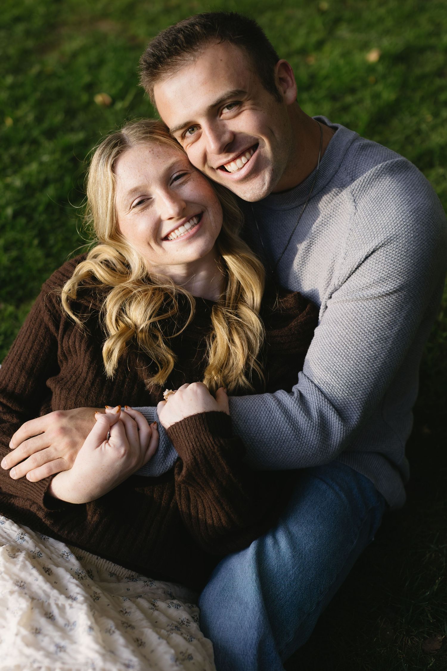 Candid outdoor portrait series showing couple cuddling on grass in natural lighting.