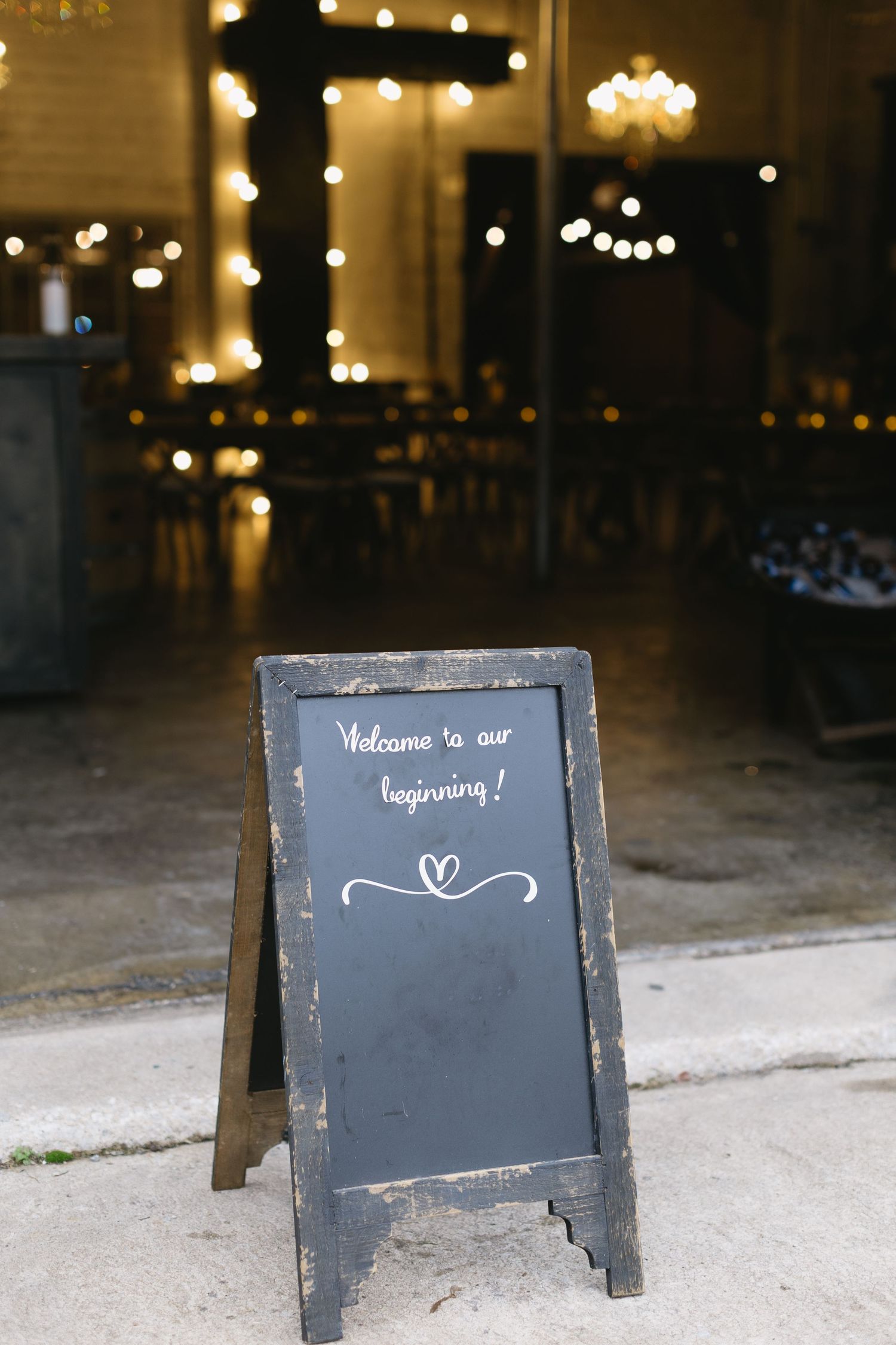 Chalkboard welcome signs with string lights create an inviting ambiance at an evening event.