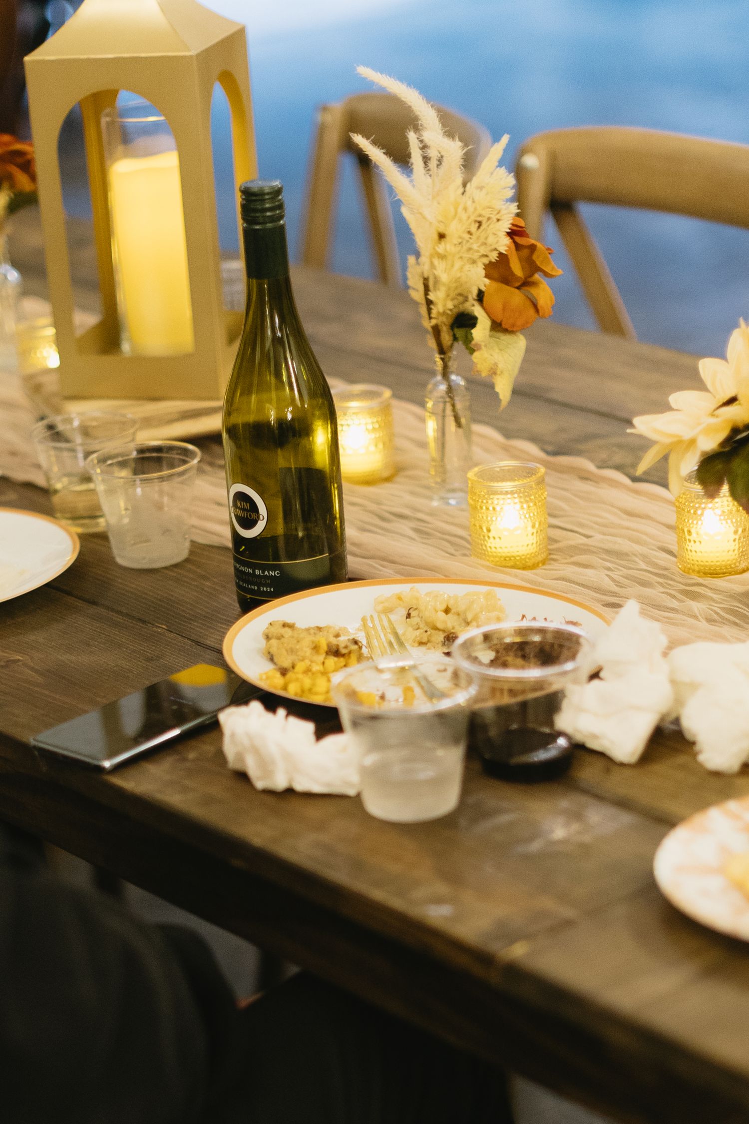 Elegant table setting with wine bottles, candles and decorative elements at dusk.