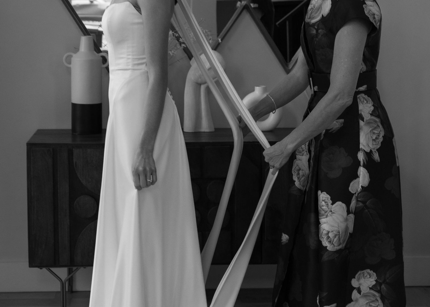 A close-up of dress adjustments being made during wedding preparations.