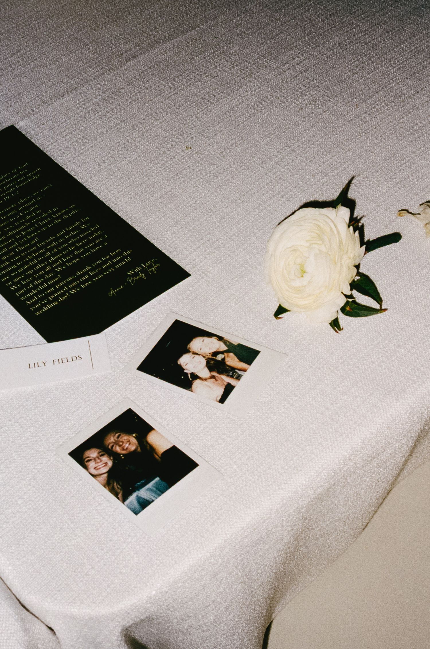 White rose and printed text cards arranged artistically on a light gray linen surface.