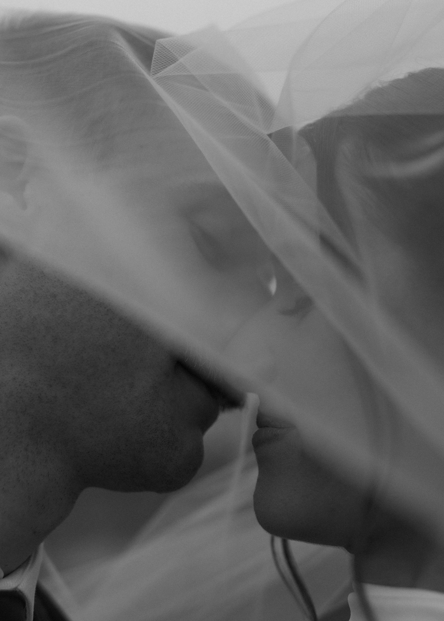 Artistic black and white close-up of flowing wedding veil fabric creating ethereal patterns.