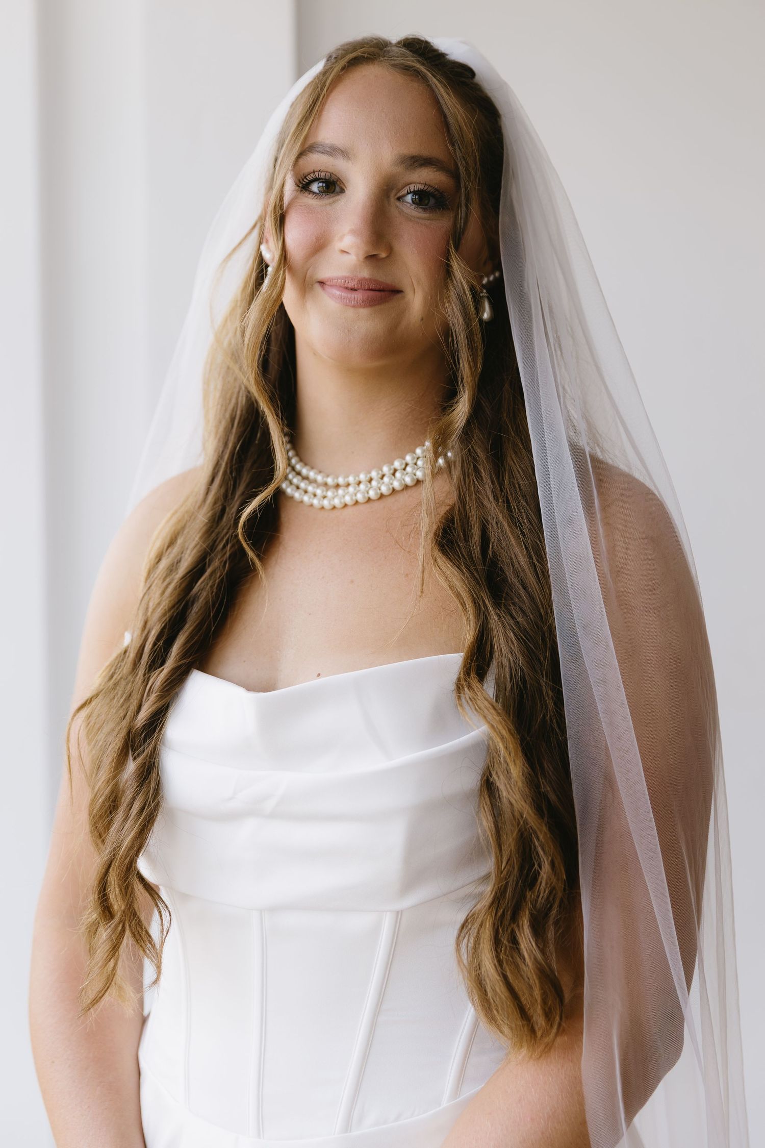 Elegant bridal portrait showcasing a classic white gown and pearl necklace.