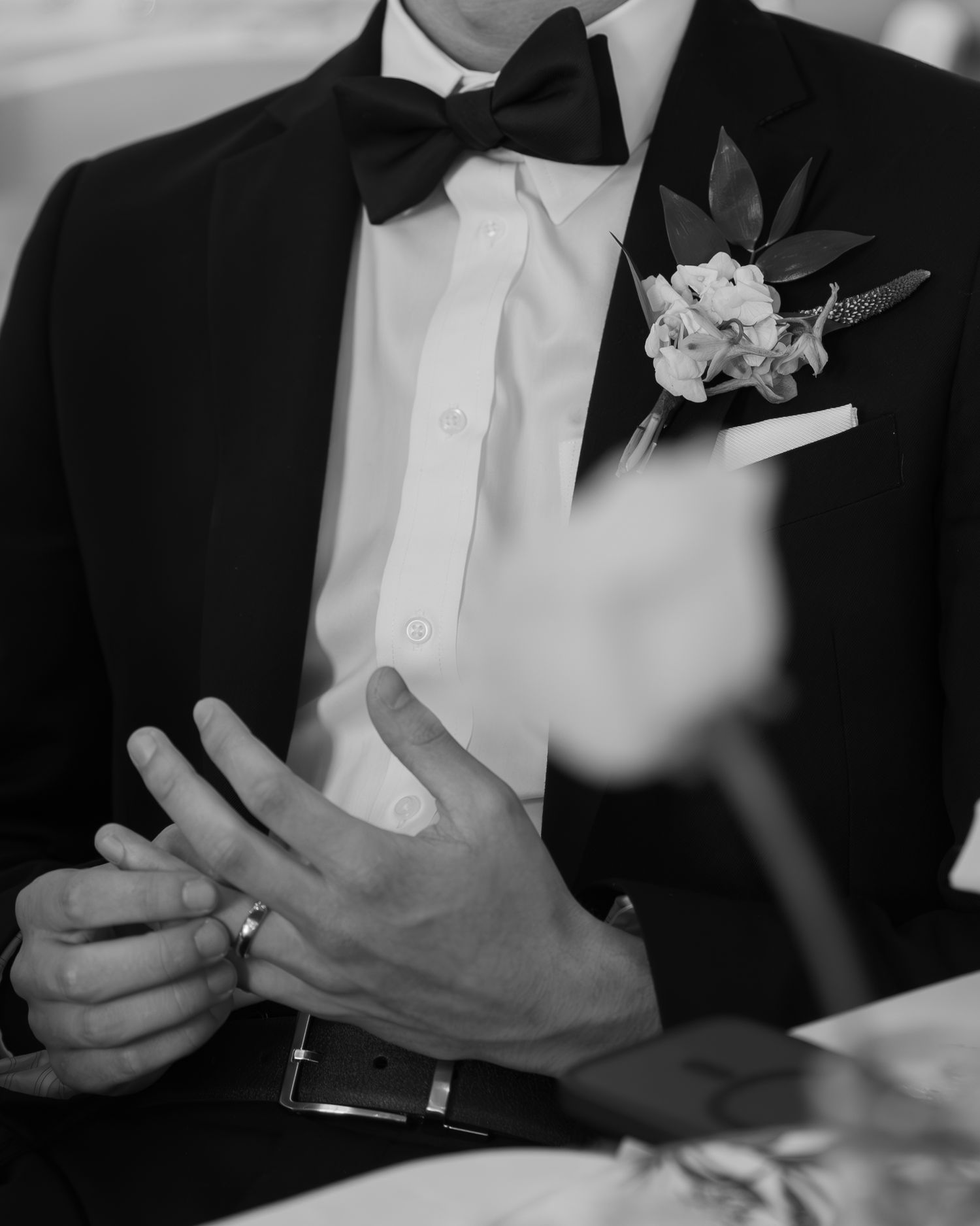 Detail of formal attire with black bow tie and white boutonniere.