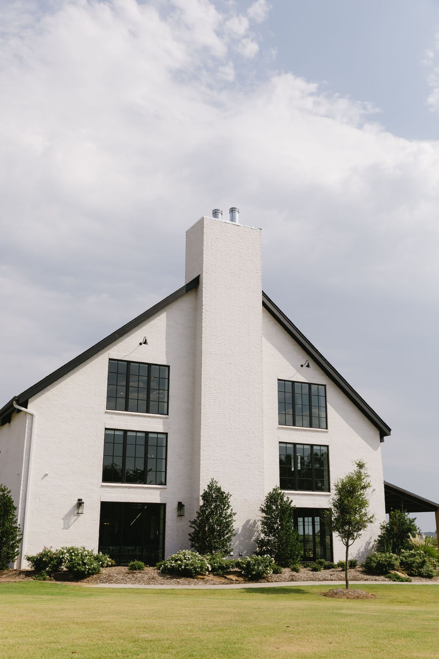 Modern white church buildings with sloped roofs and large windows stand in a row against a cloudy sky.