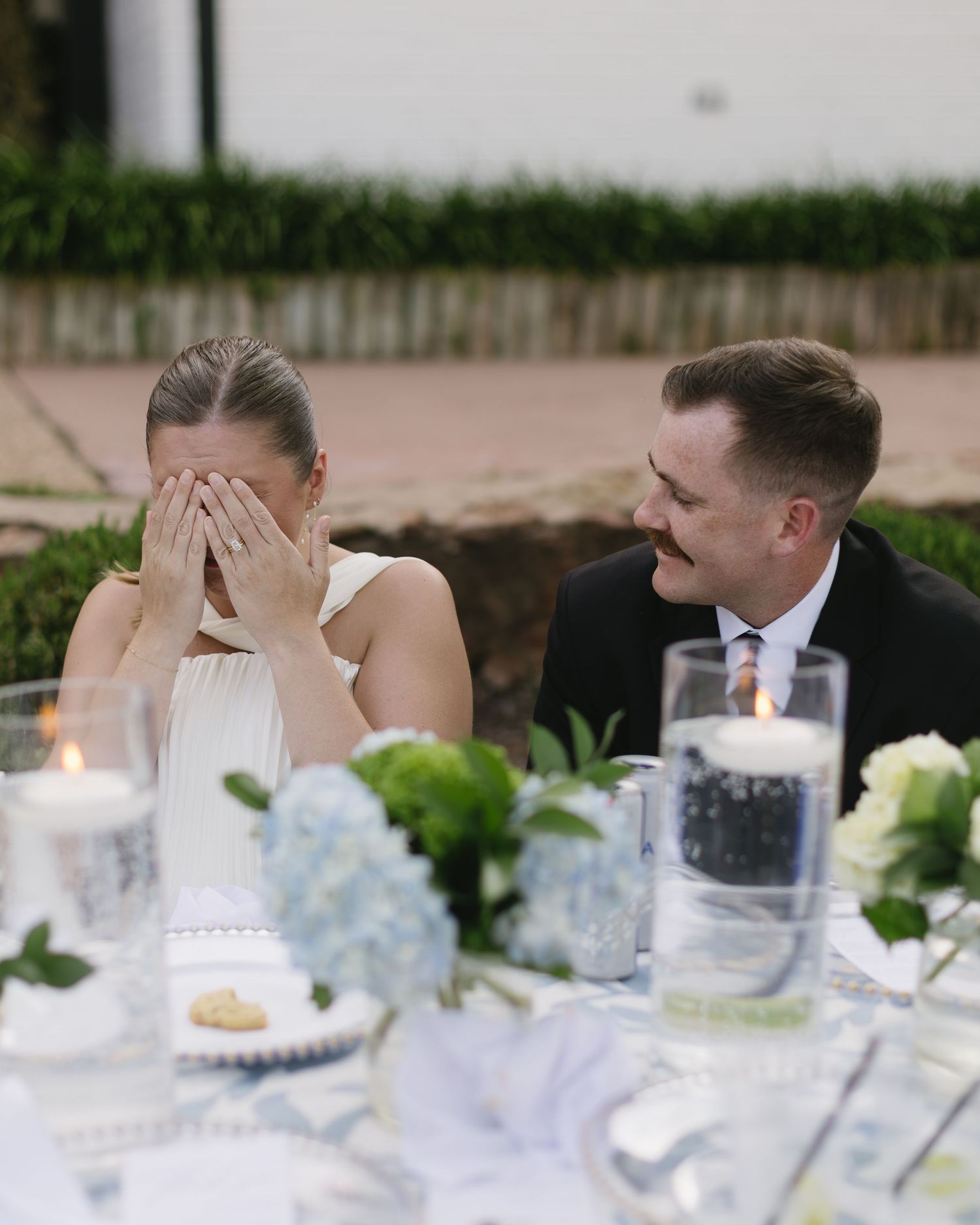 Wedding reception table decorated with white and blue florals, glassware and elegant place settings.