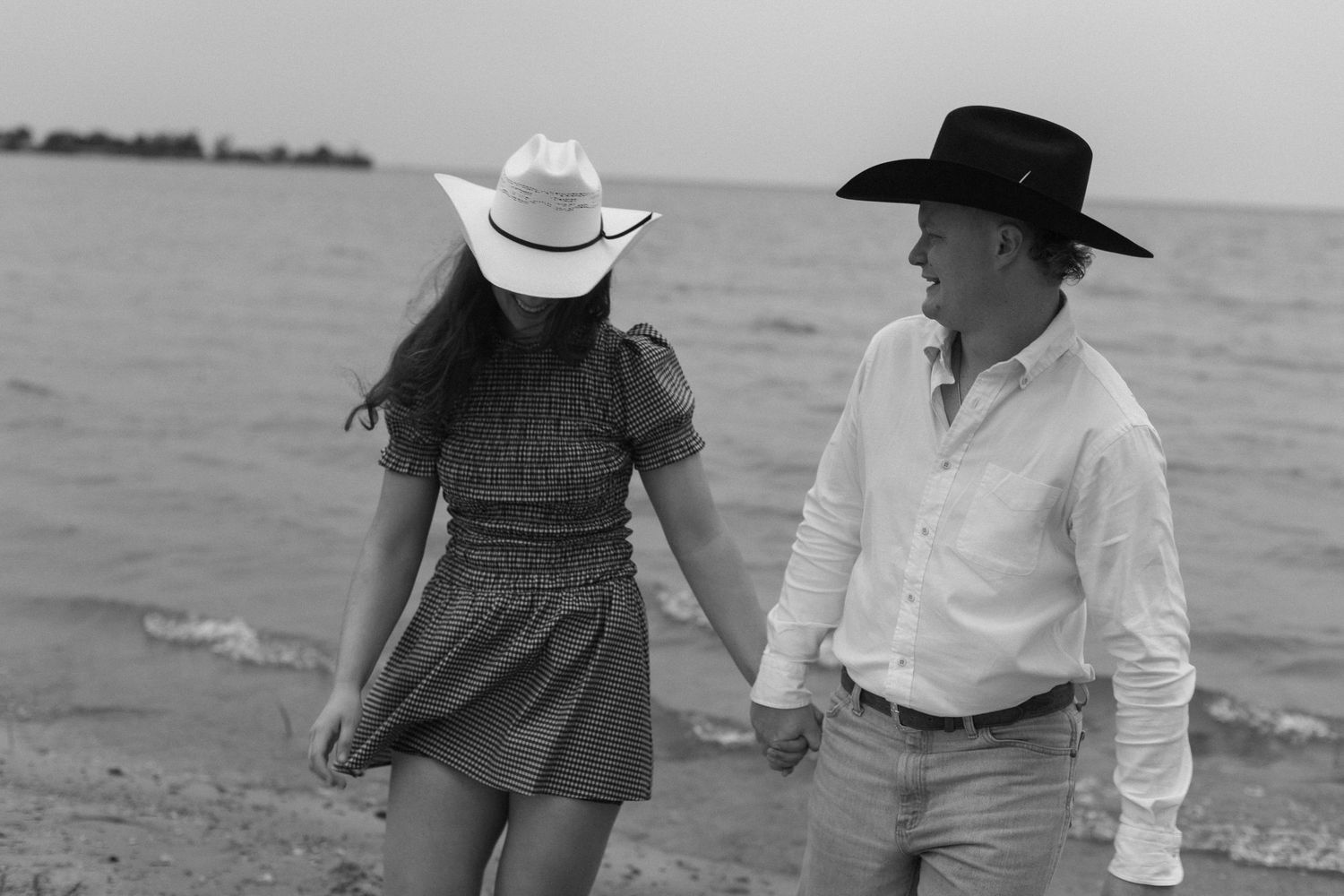 Romantic walk along the beach with cowboy hats and casual attire.