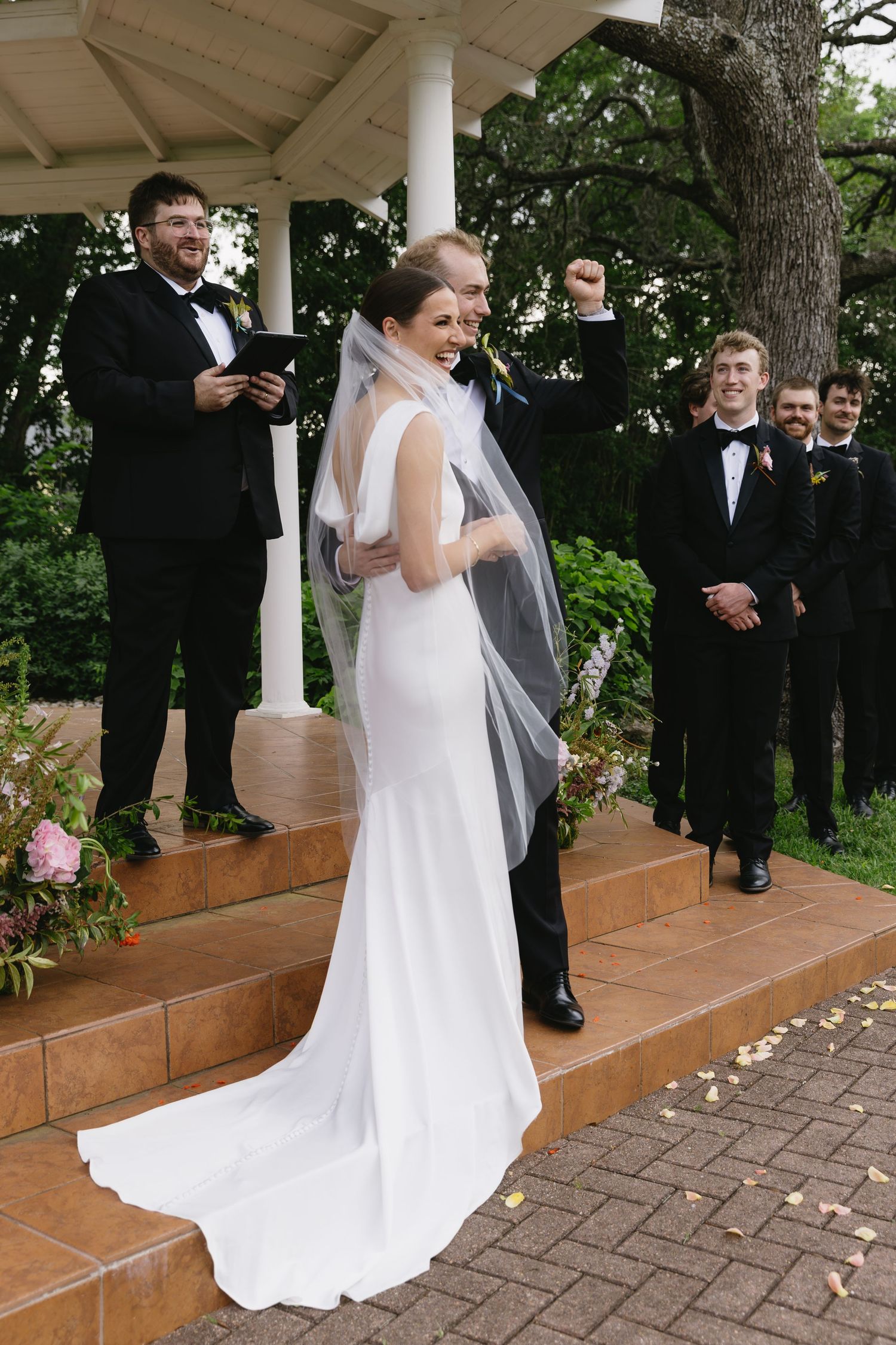 Wedding ceremony sequence on a brick patio with white columns and trees in background.