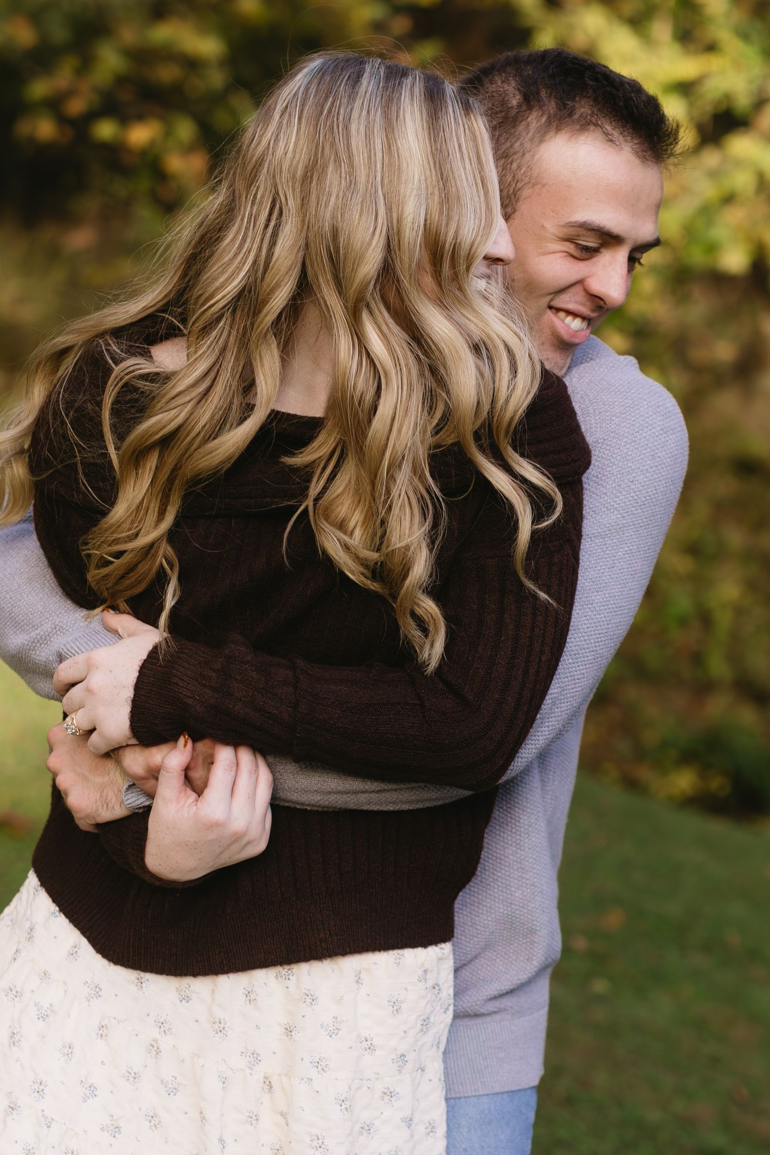 Intimate embrace captured between couple in casual autumn attire outdoors.