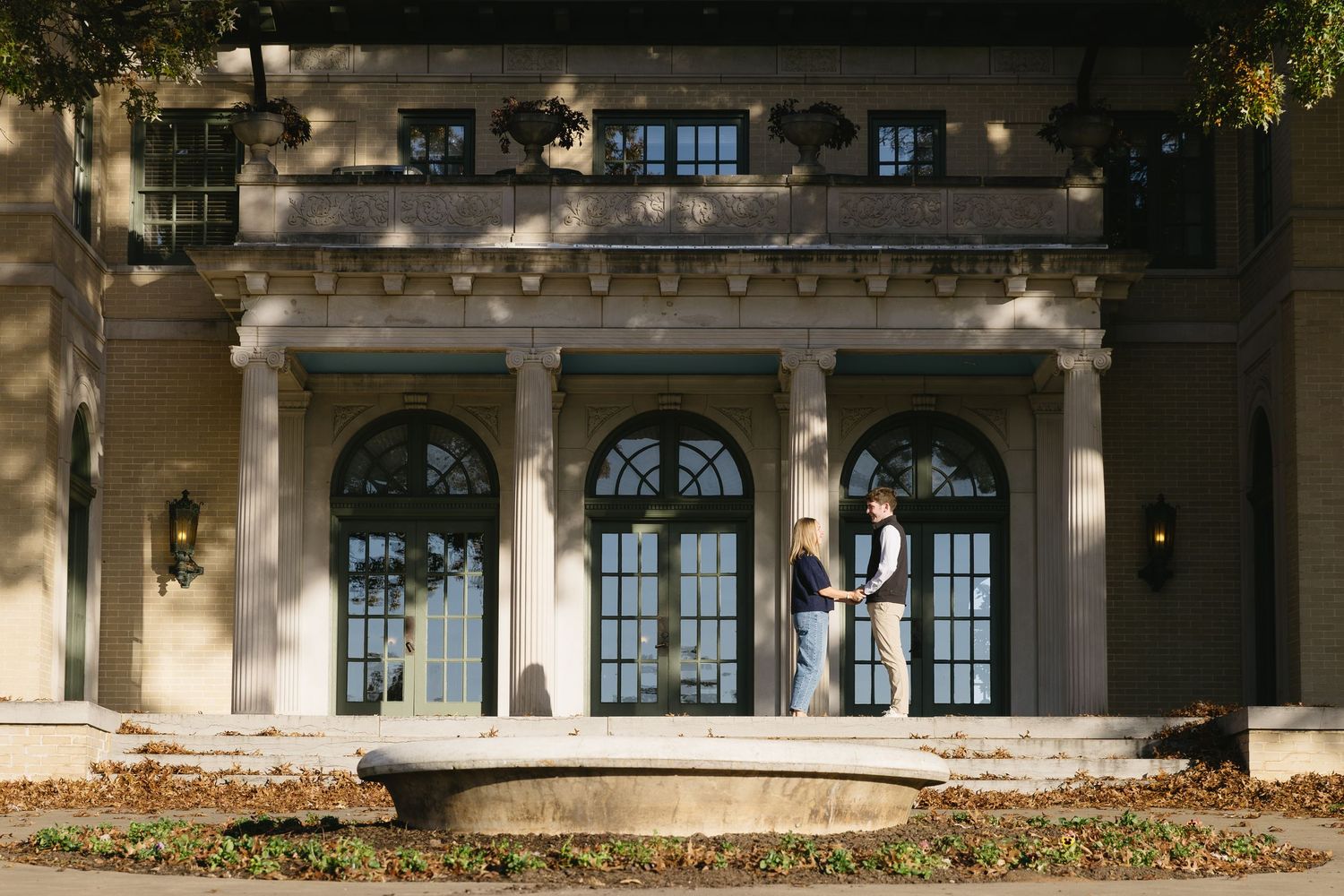 Exterior view of a grand historic building with arched windows and columns at dusk.