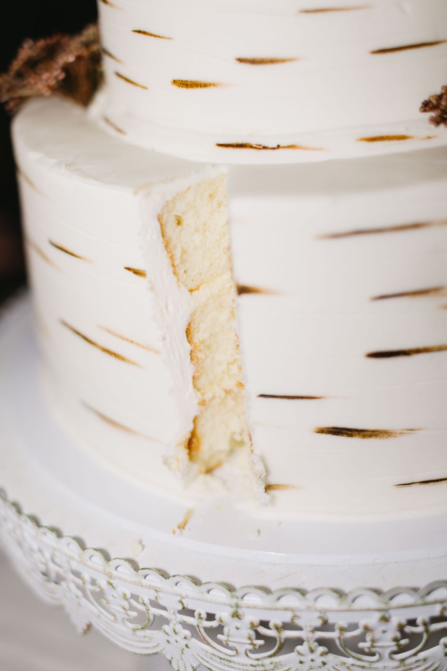 Close-up detail of a white birch-themed wedding cake with textured frosting on an ornate stand.