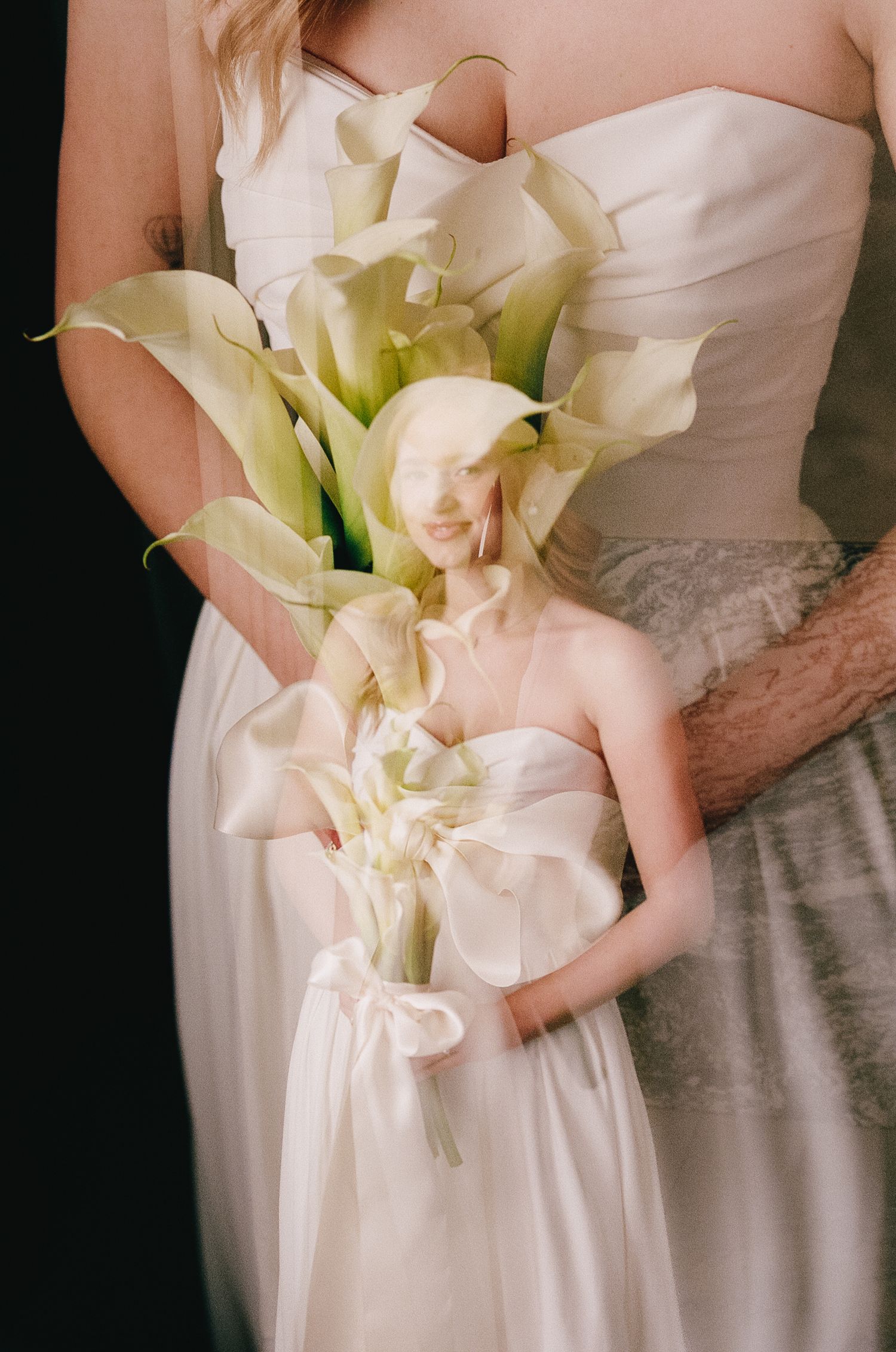 Detail shot of white calla lily wedding bouquet against bridal gown.