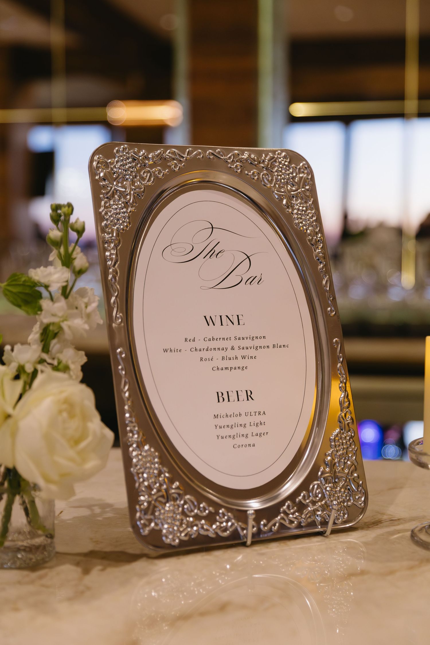 Ornate silver frames display elegant wedding menu cards with calligraphy text on a decorated table.