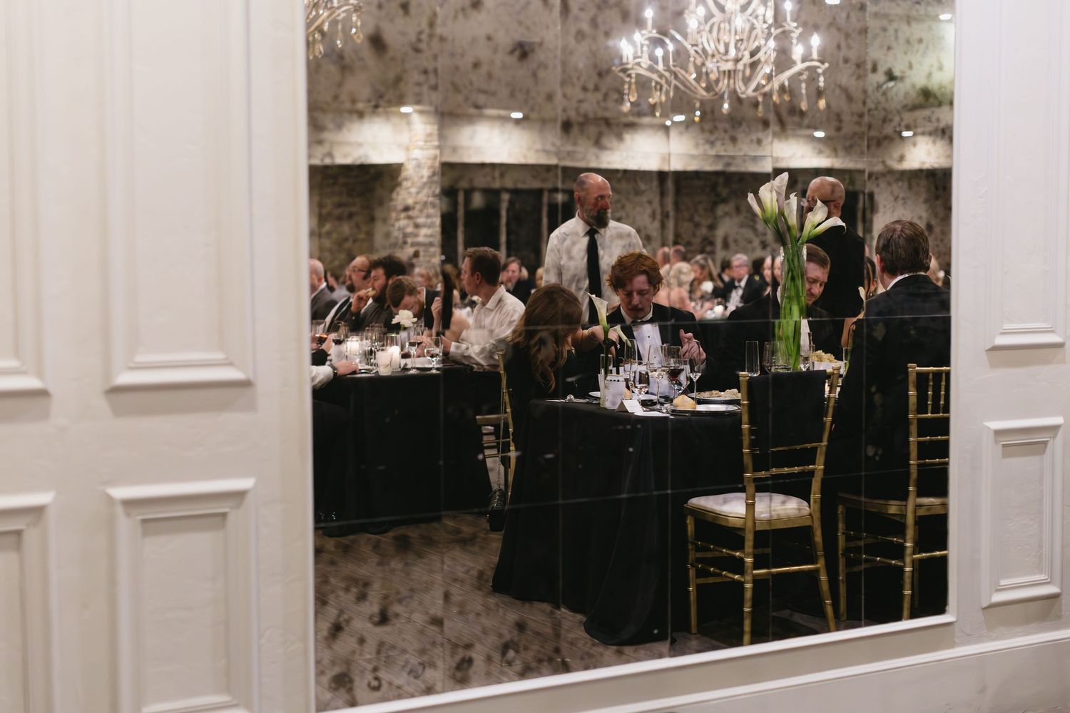 Interior view of an elegant reception hall with white pillars and chandeliers.