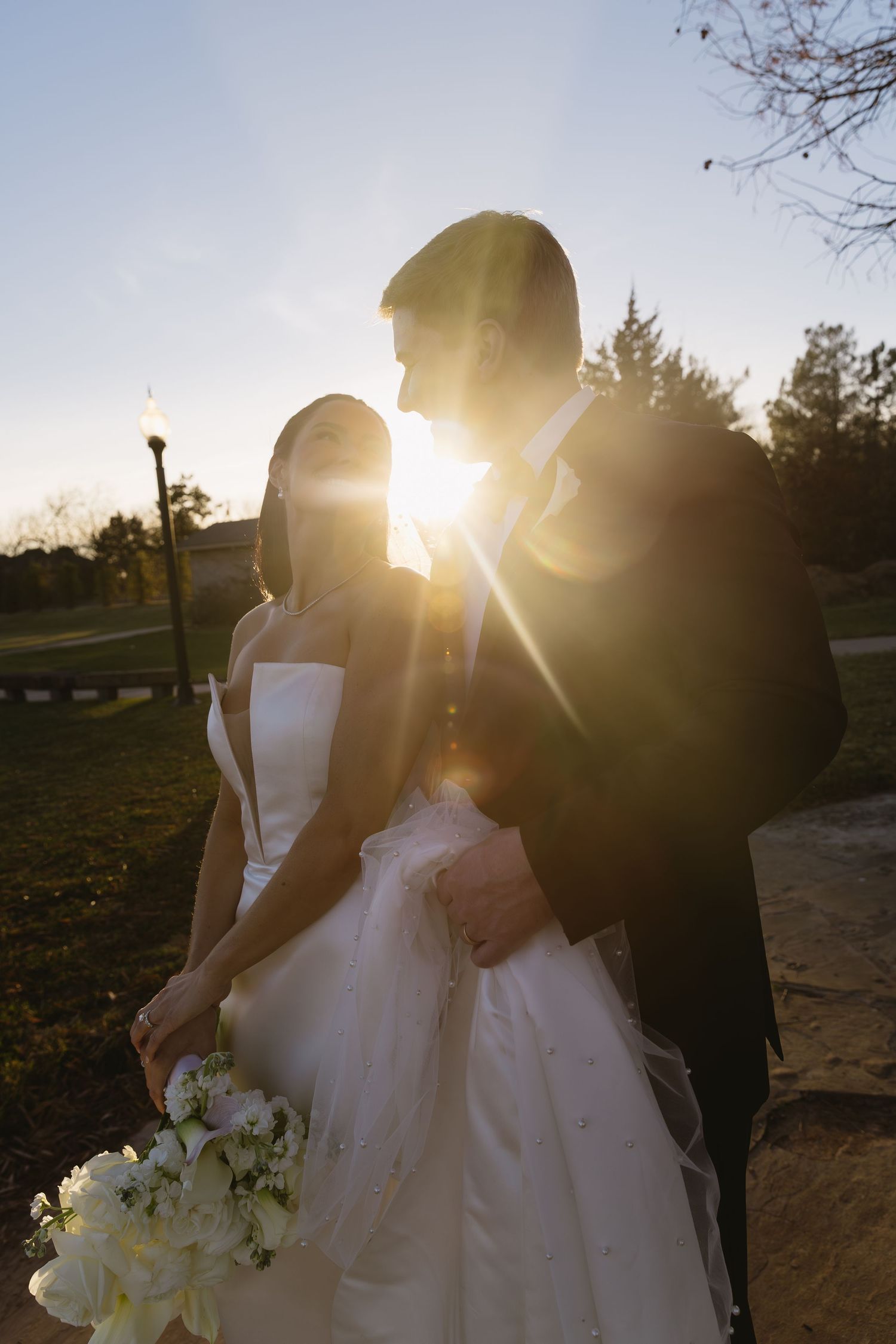 Silhouettes of wedding party against golden sunset light holding bouquets.