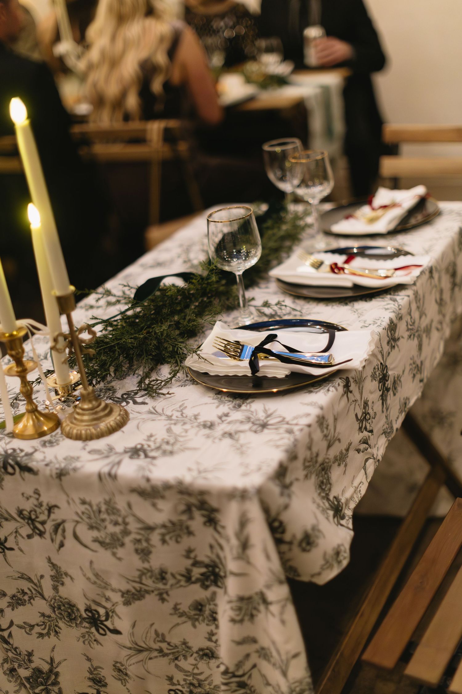 Elegant wedding reception table setting with marbled tablecloth and evergreen decorations.