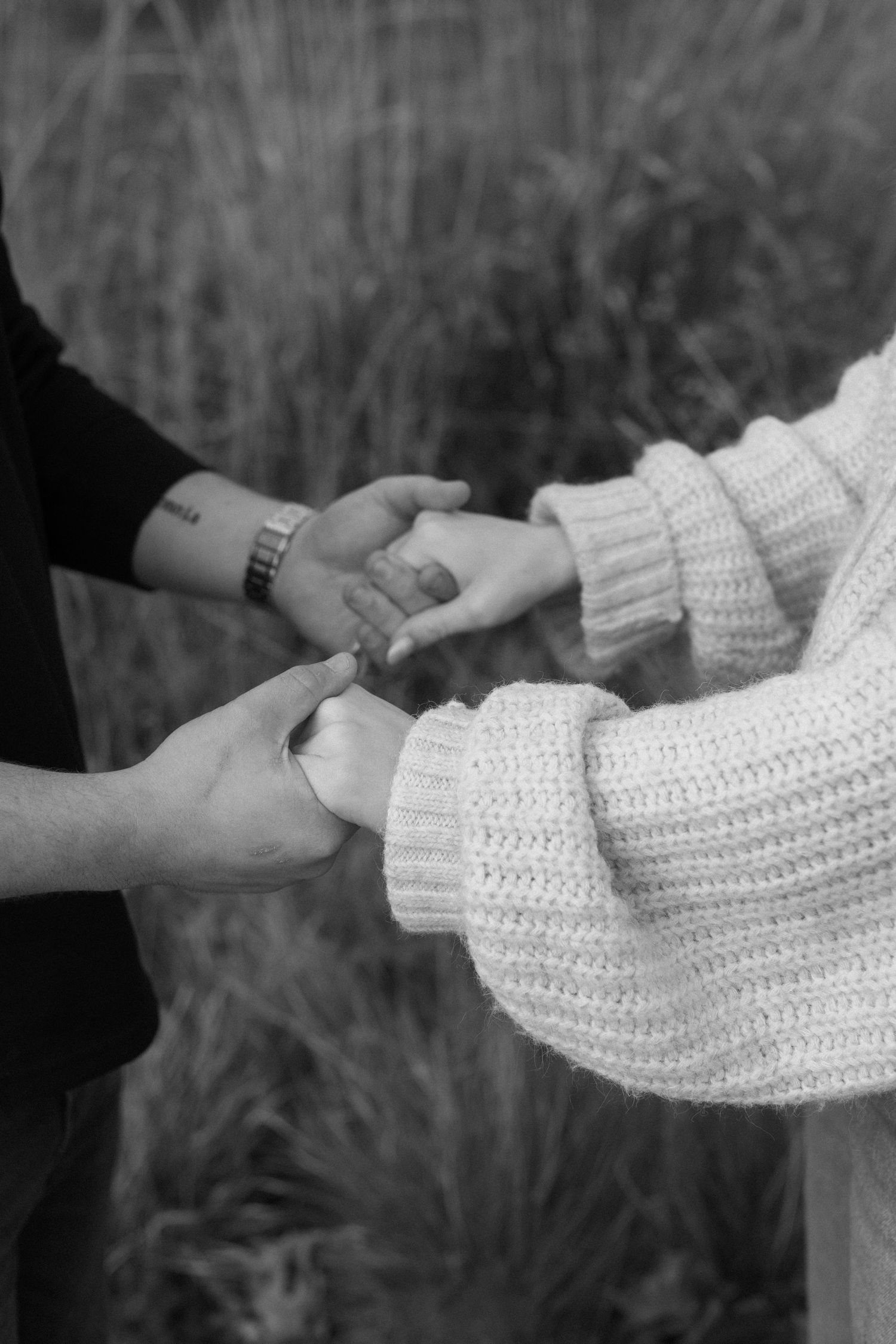 Close-up shots of hands holding each other while wearing a white knitted sweater sleeve.