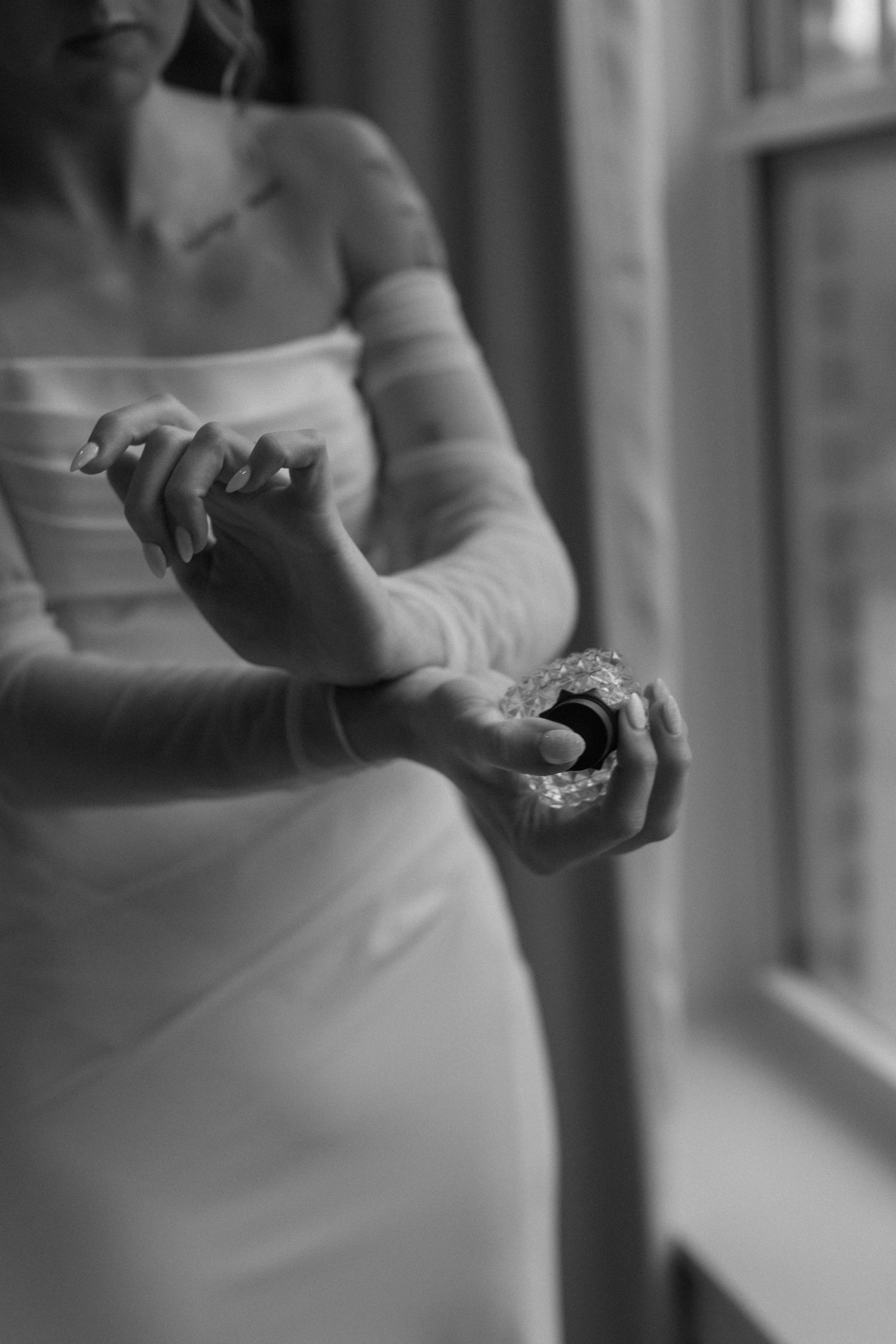 Close-up of hands adjusting jewelry in black and white photography.