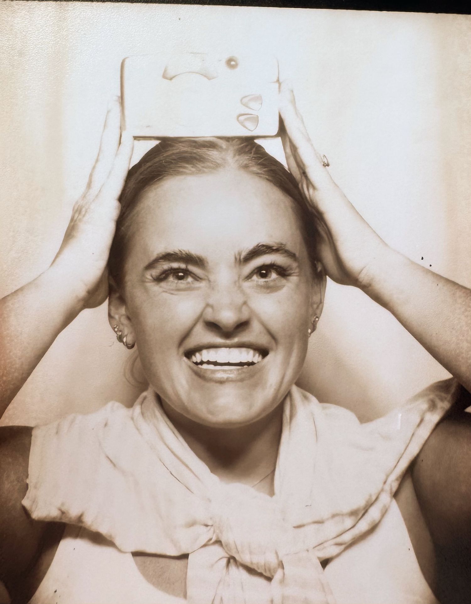 A vintage sepia photograph shows someone in a nurse's cap and uniform smiling brightly at the camera.