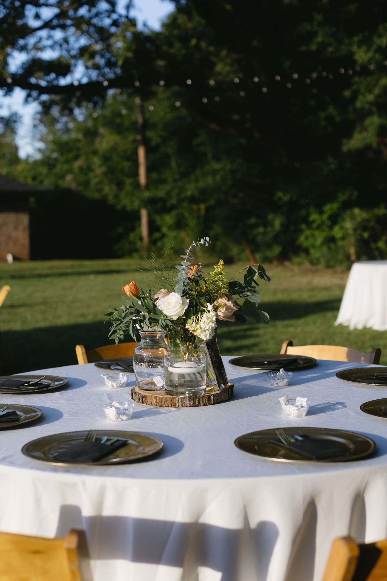 Round reception tables decorated with rustic centerpieces featuring wood slices and mason jar flower arrangements.