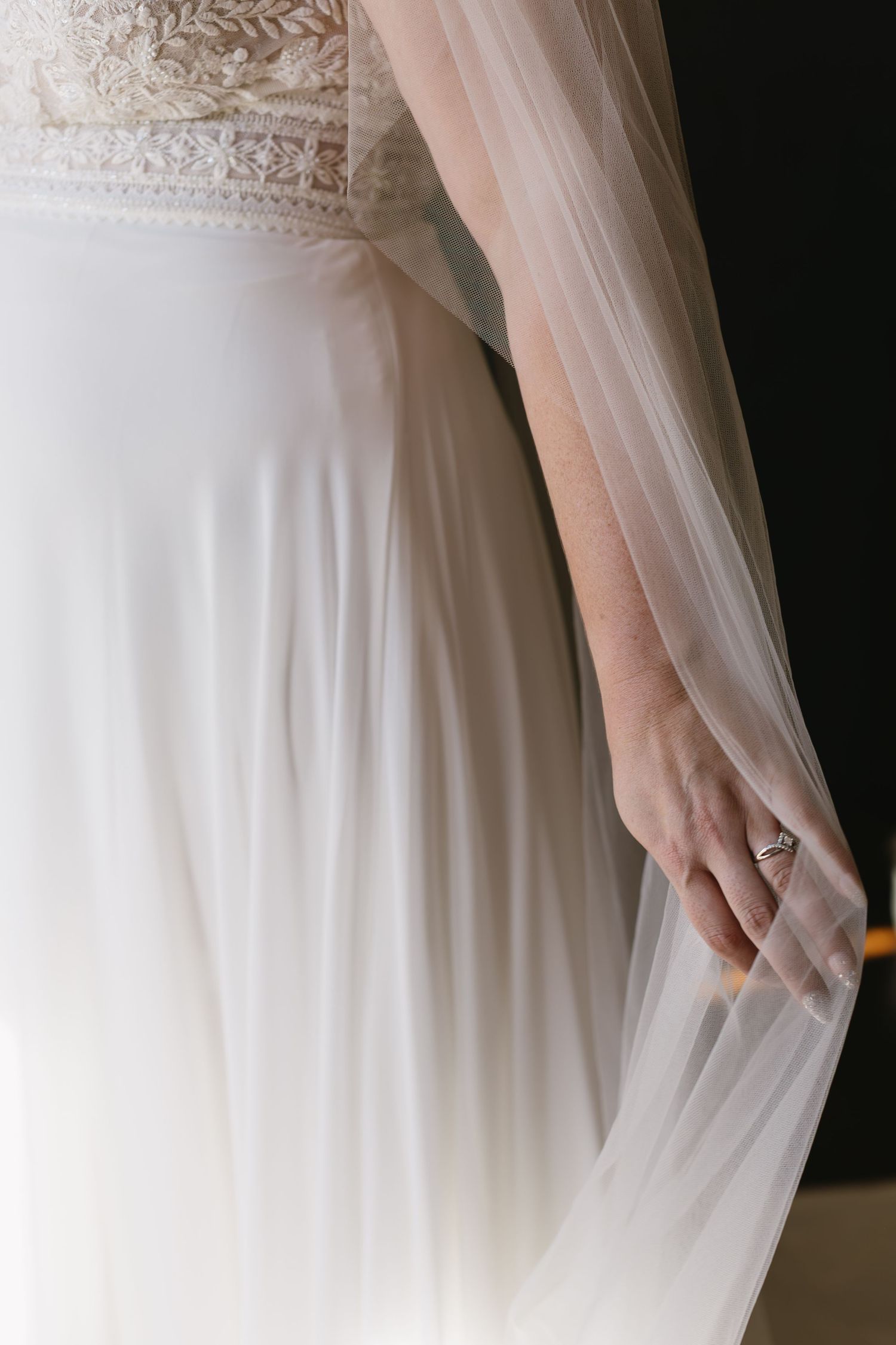 Close-up detail of delicate white lace and tulle on a wedding dress sleeve.