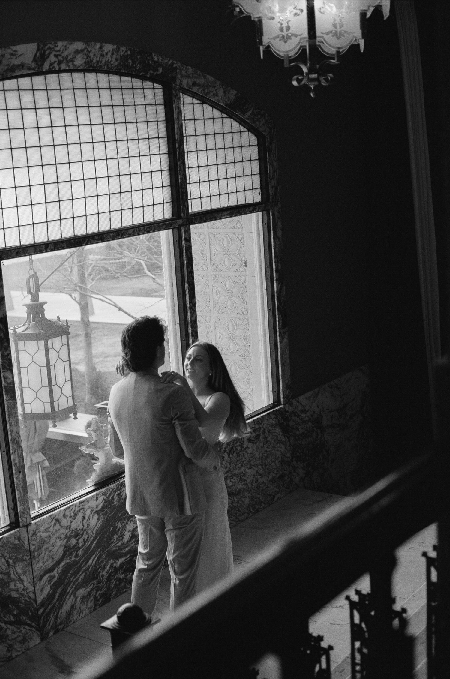 A sequence of black and white photos showing a couple walking together through an interior space with windows.