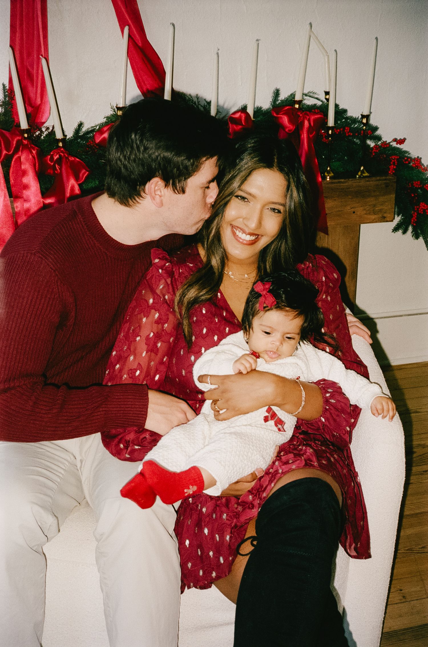 Family holiday portrait session with coordinating outfits in a cozy indoor setting.